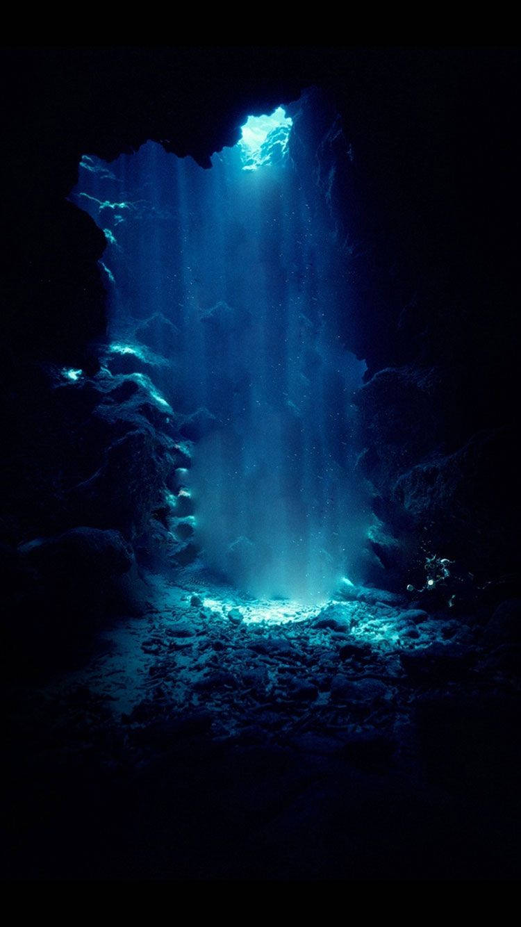 A Blue Light Shines Through A Cave Background