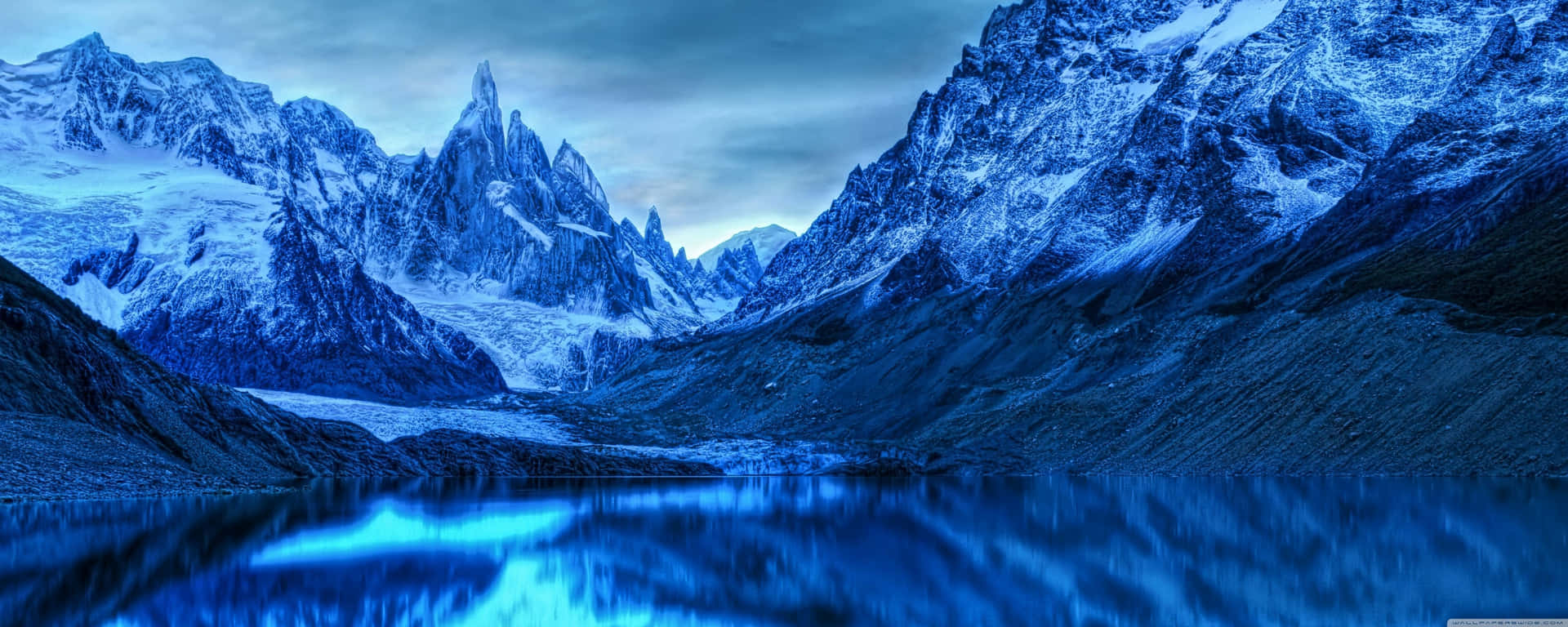 A Blue Mountain Range With A Lake In The Background Background