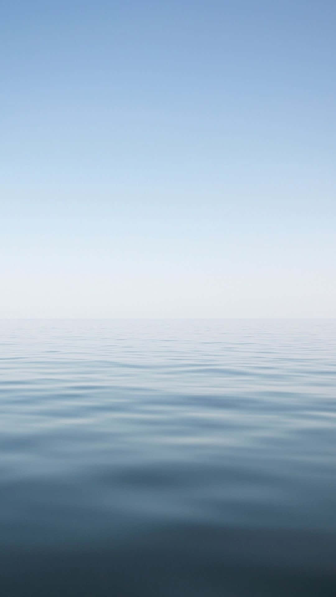 A Blue Ocean With A White Sky Background