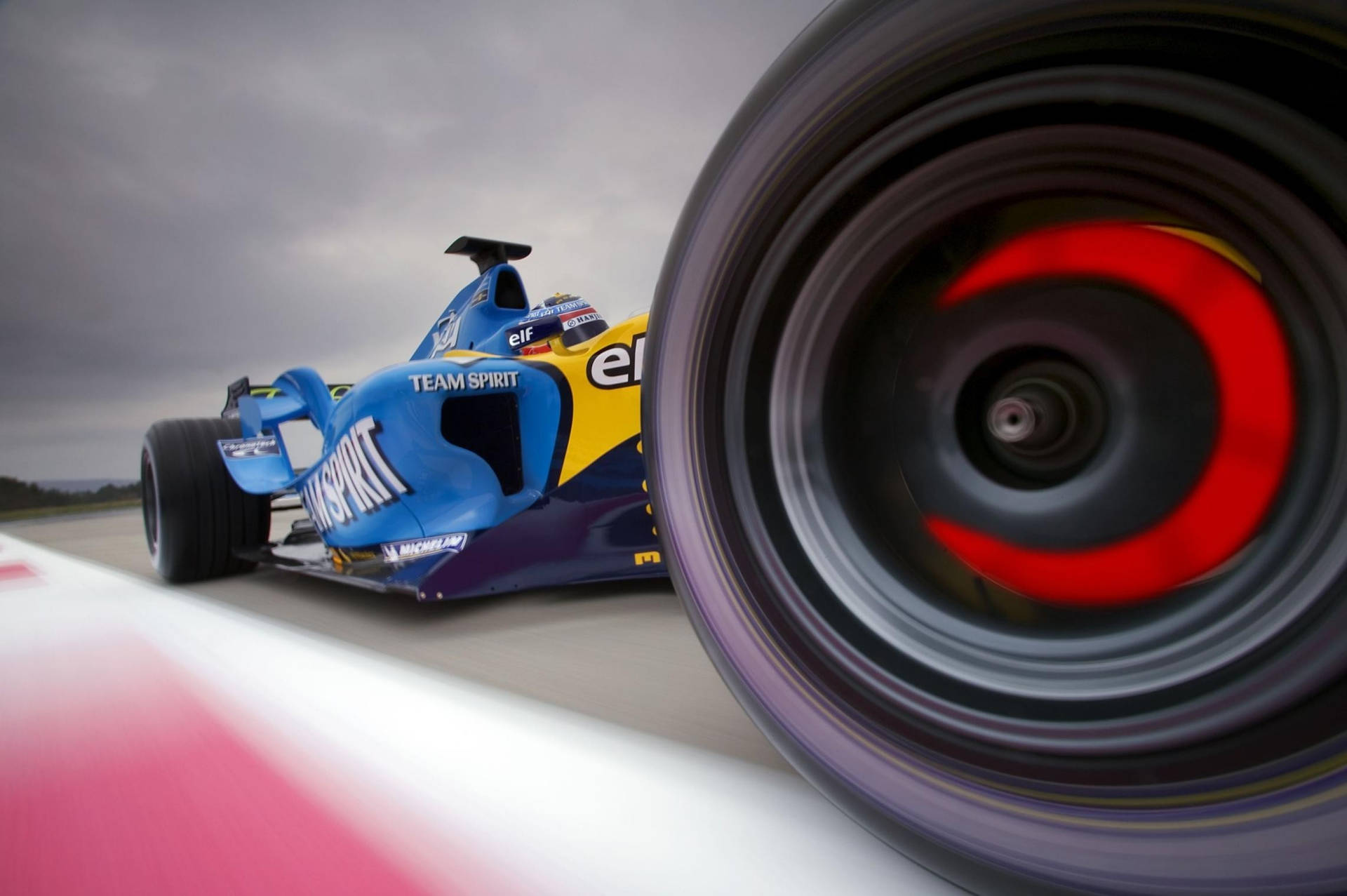 A Blue Racing Car With Red Wheels On The Track Background