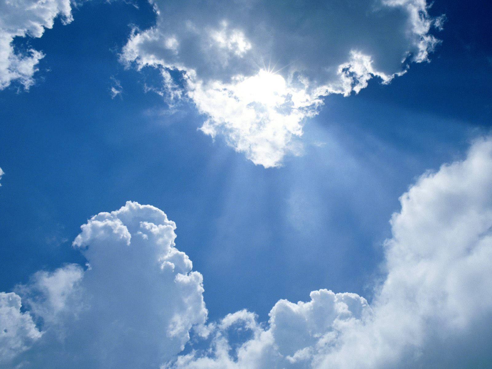 A Blue Sky With Clouds And Sun Shining Through Background