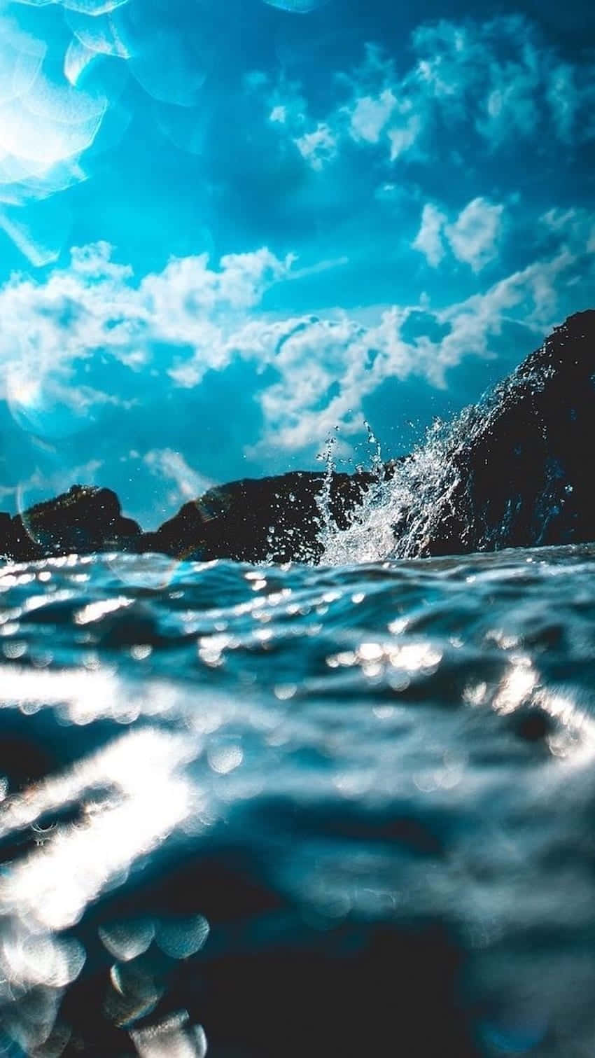 A Blue Sky With Clouds And Water Splashing Background