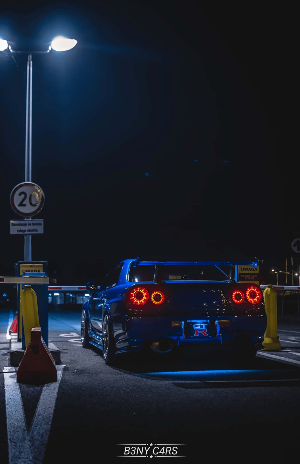 A Blue Sports Car Parked In A Parking Lot At Night