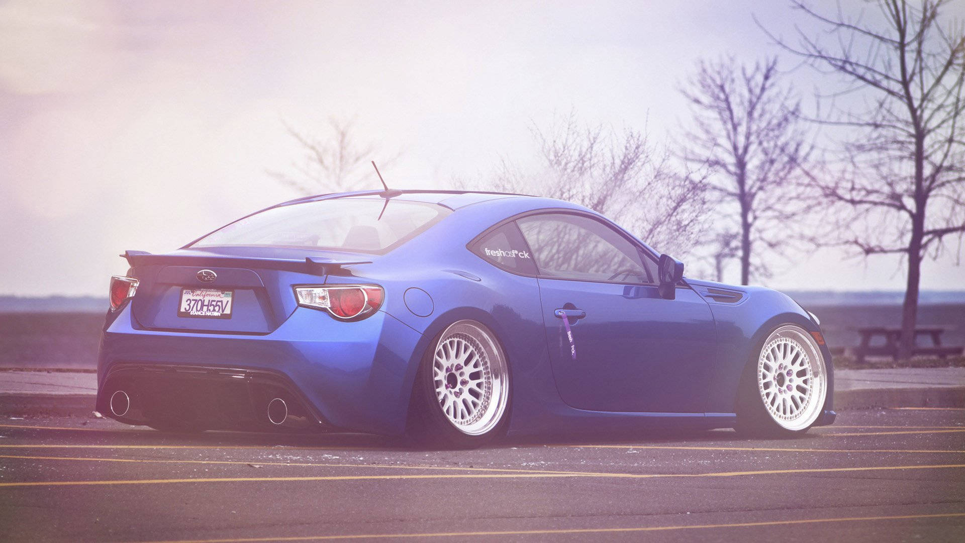 A Blue Sports Car Parked In A Parking Lot Background