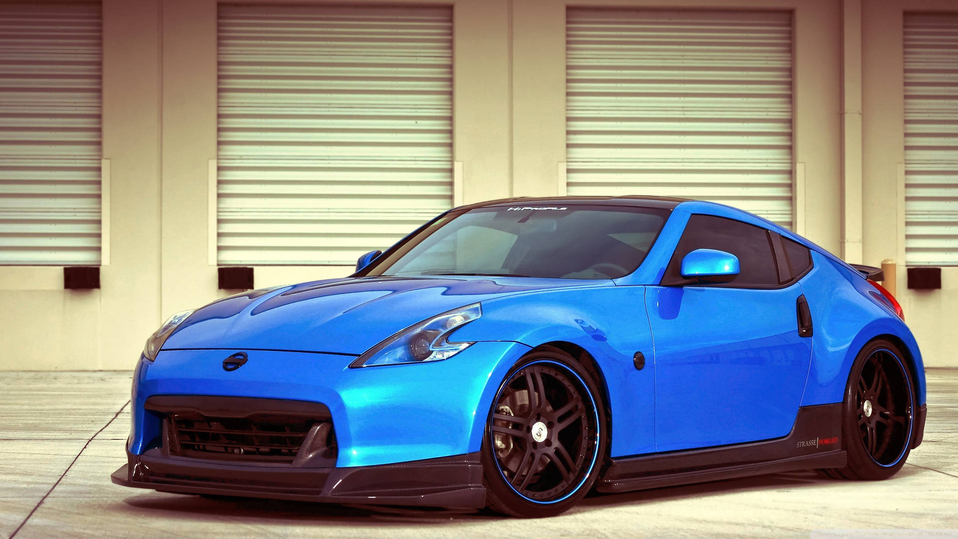 A Blue Sports Car Parked In Front Of A Garage Background