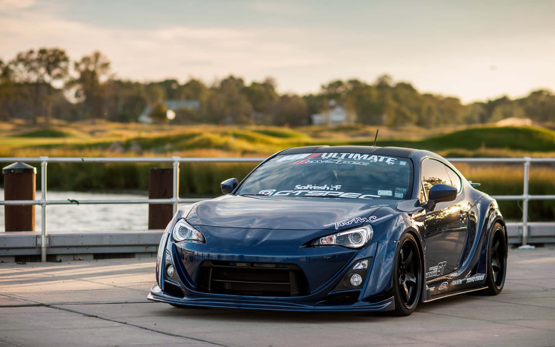 A Blue Sports Car Parked On A Dock Background