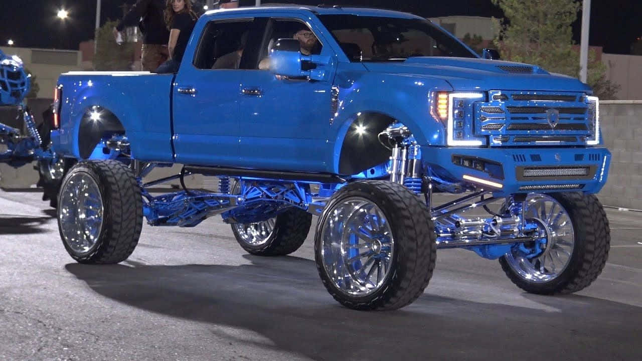 A Blue Truck With A Large Tire On It Background