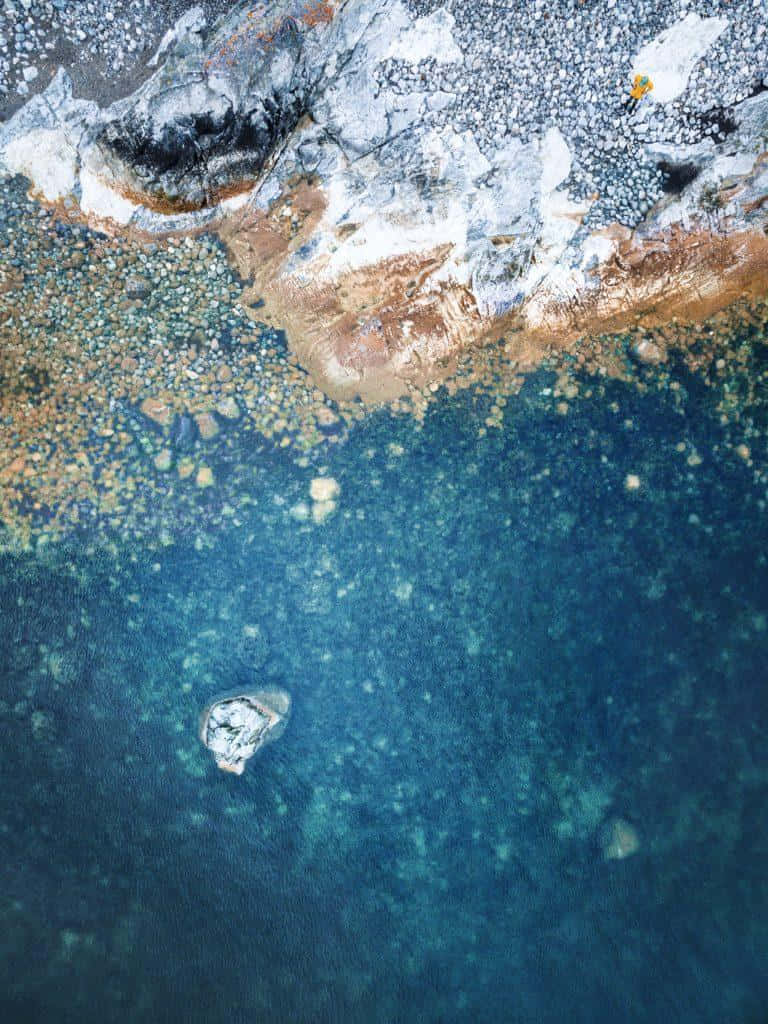 A Blue Water With A Rock In It Background