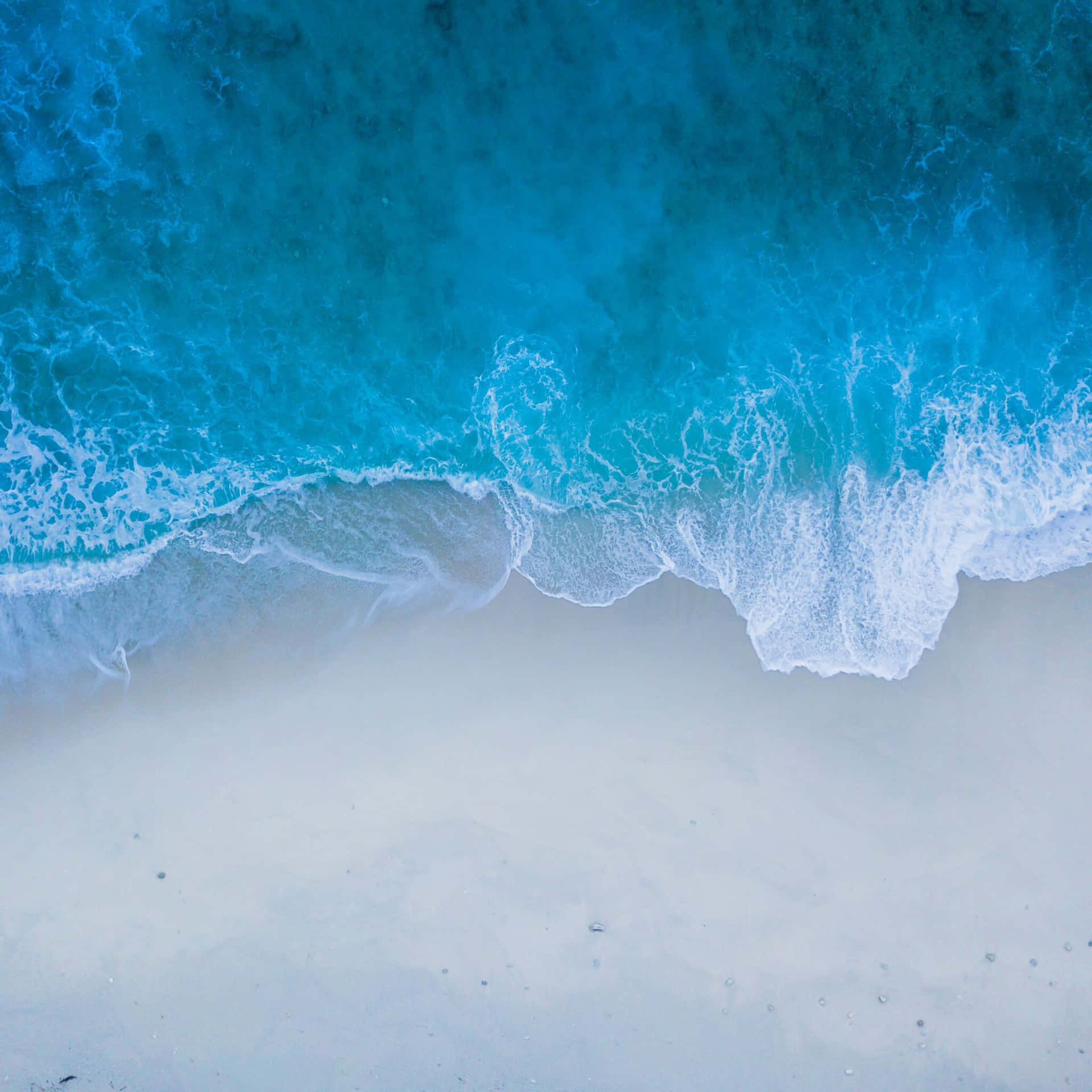 A Blue Wave Is Crashing On The Beach Background