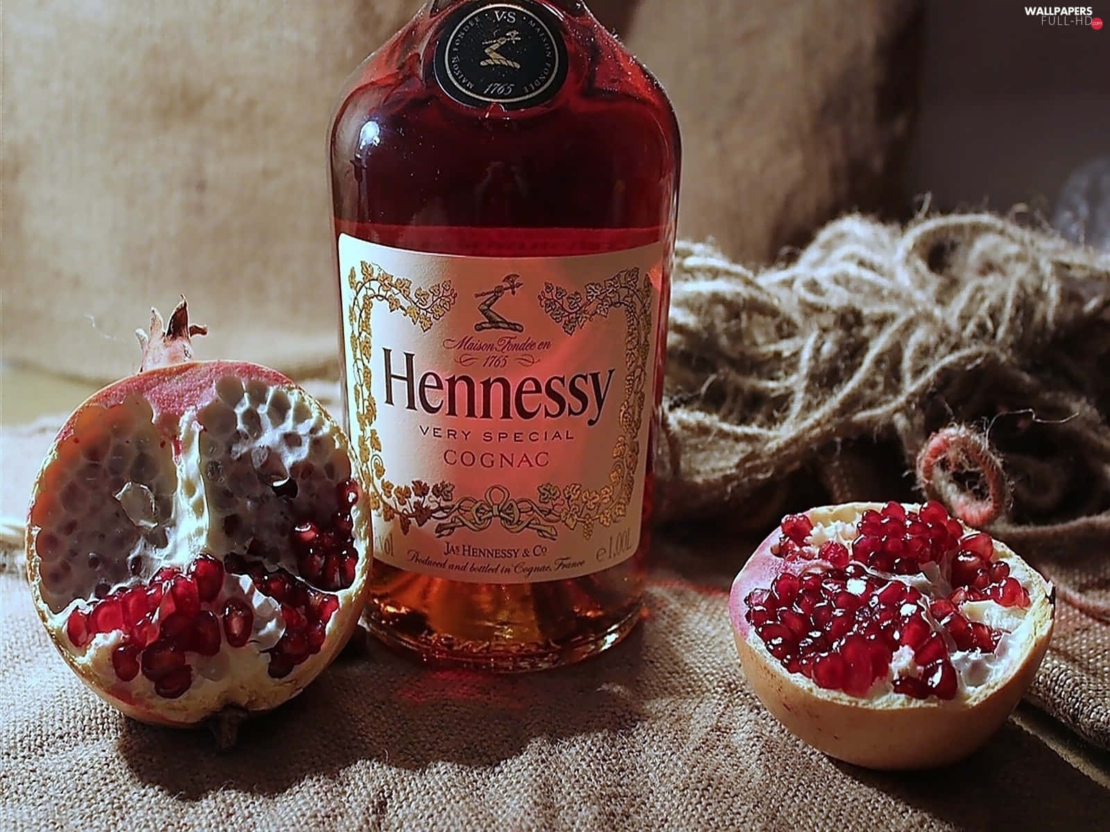 A Bottle Of Hennessy Rum With A Pomegranate Background