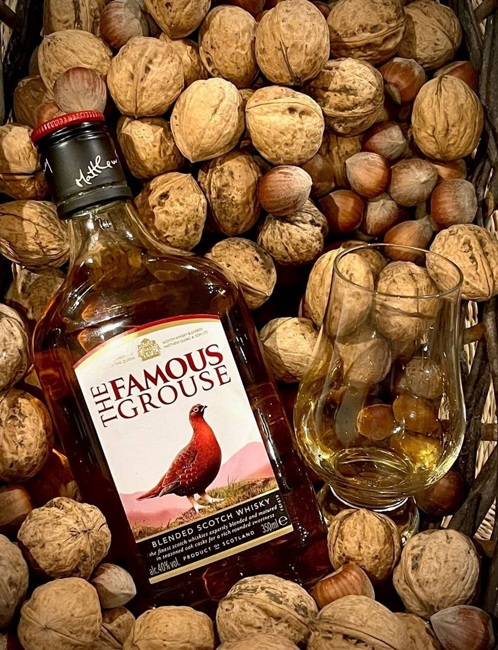 A Bottle Of The World-famous Blended Scotch, Famous Grouse Whisky Against A Warm Backdrop Background