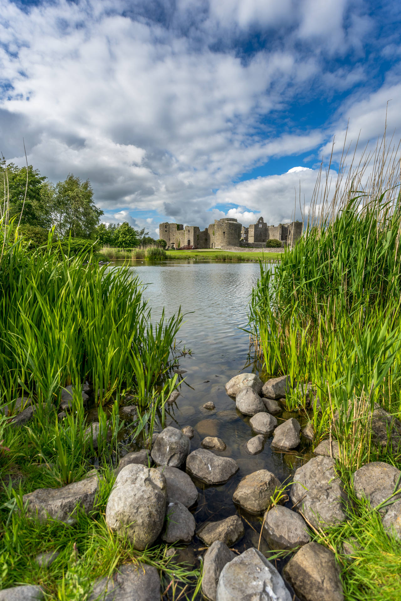 A Breathtaking View Of The Lake And Castle At Sunset Background