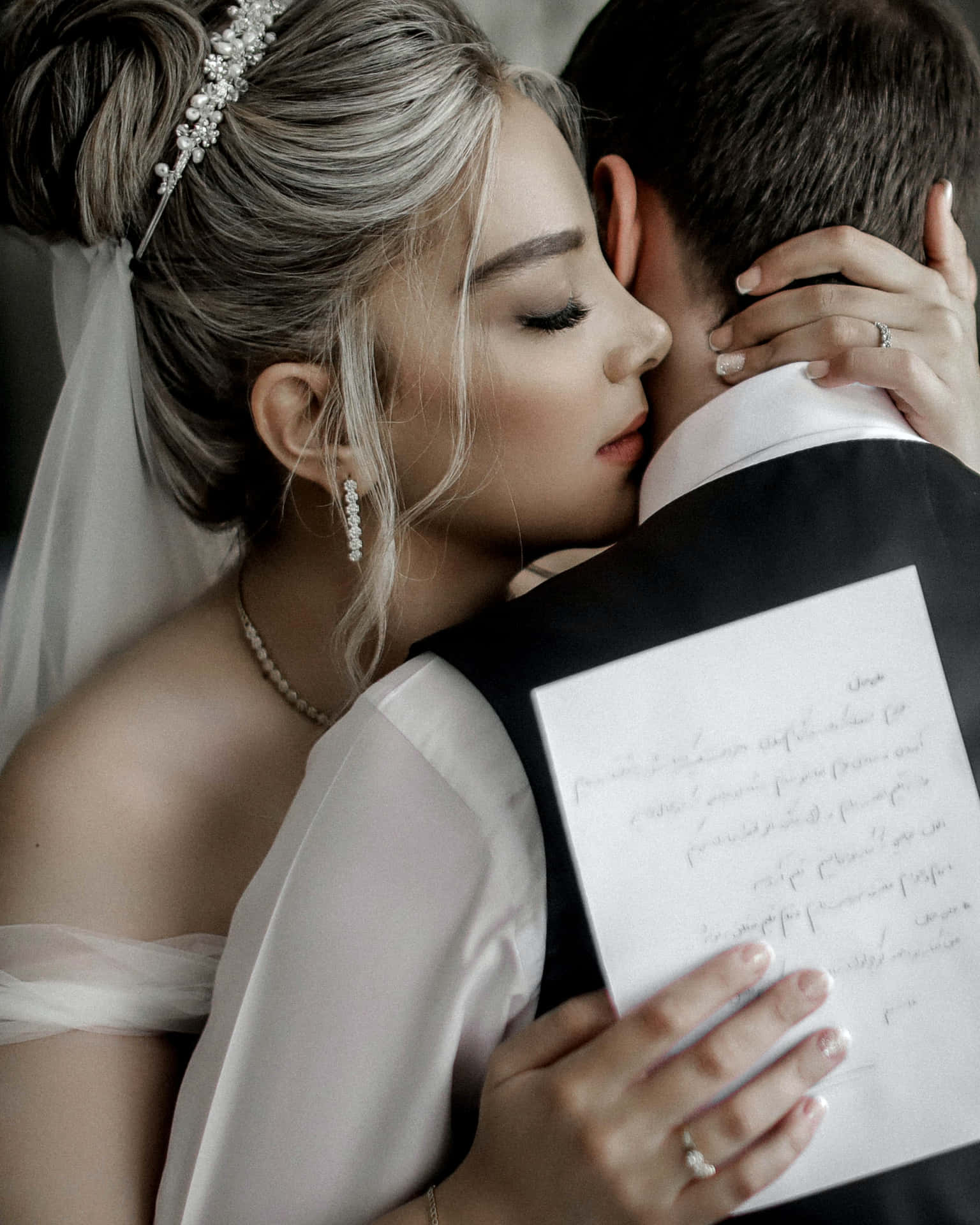 A Bride And Groom Hugging Each Other While Holding A Piece Of Paper