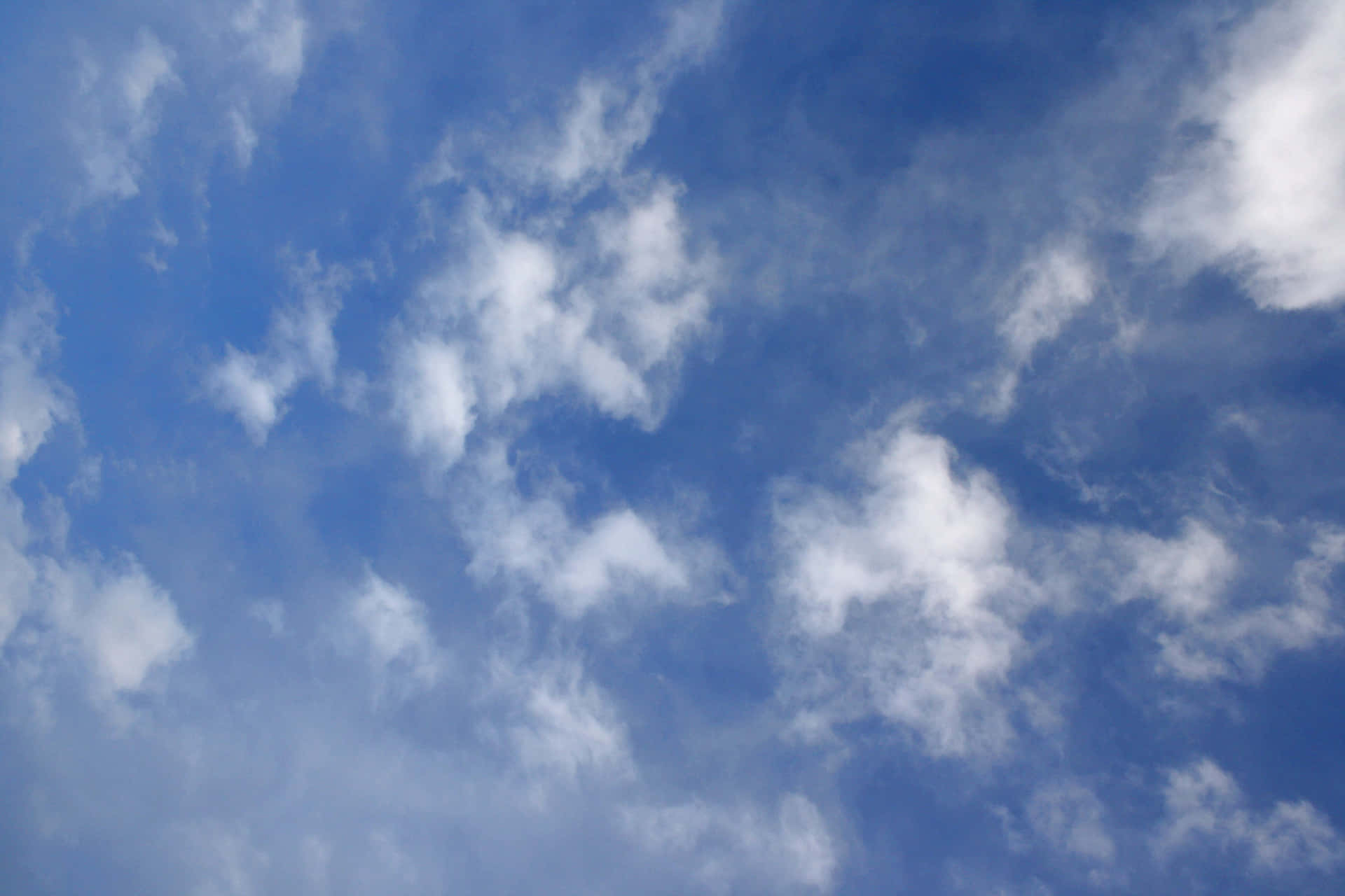 A Bright Blue Sky, Scattered With Cottony Clouds Background