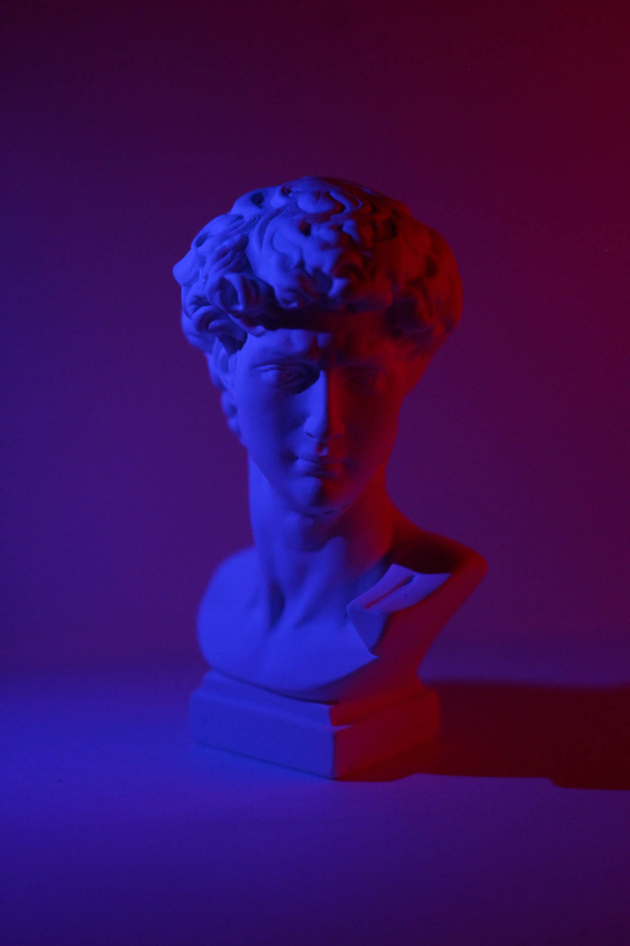 A Bust Of David With Blue And Red Lights Background