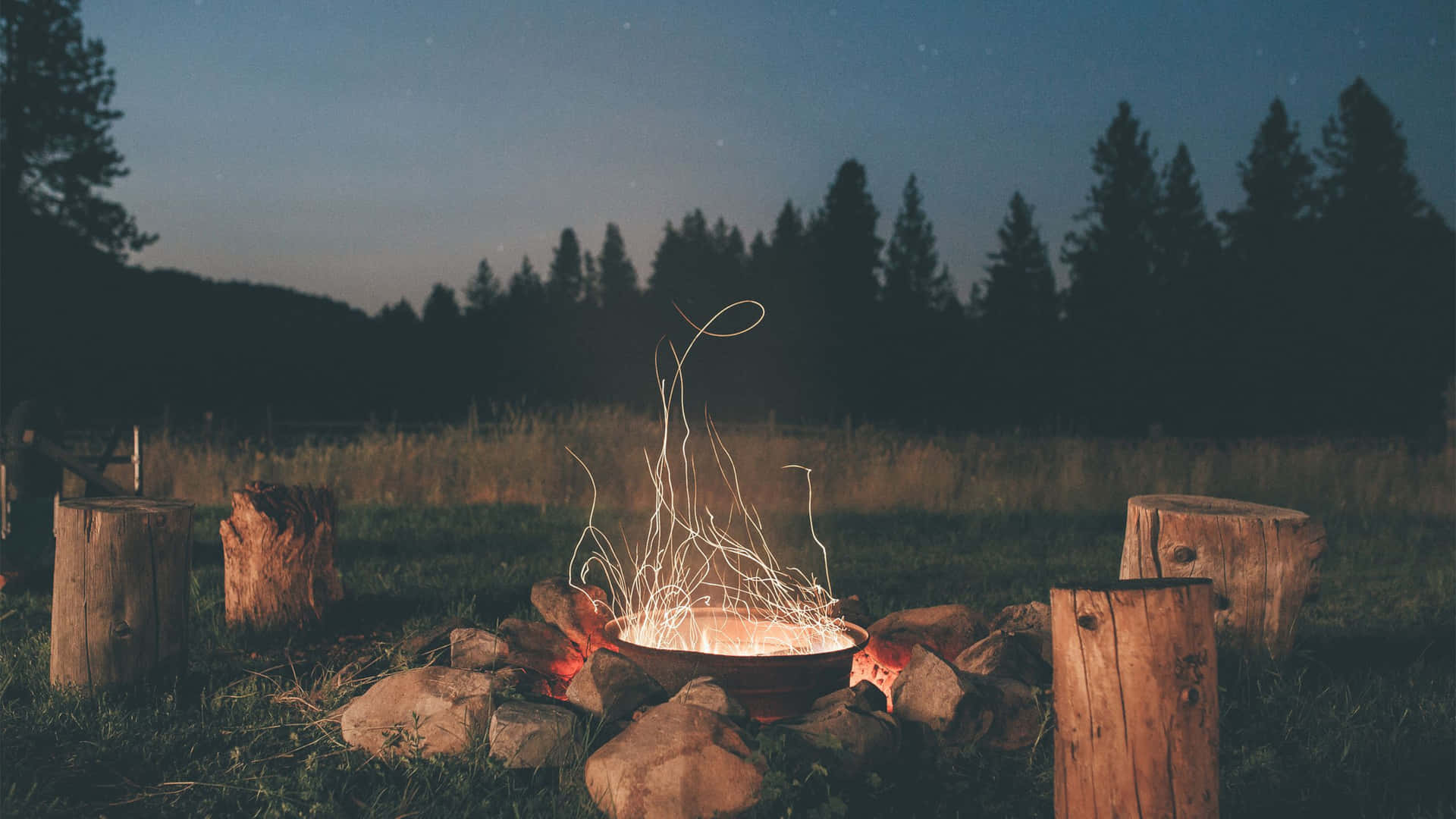 A Campfire In The Middle Of A Field At Night Background