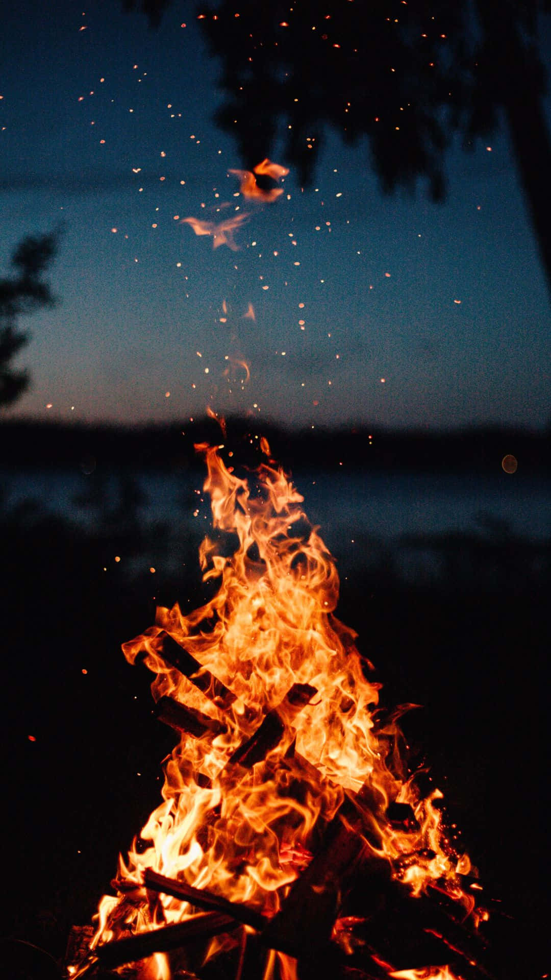 A Campfire With Flames In The Night Sky Background