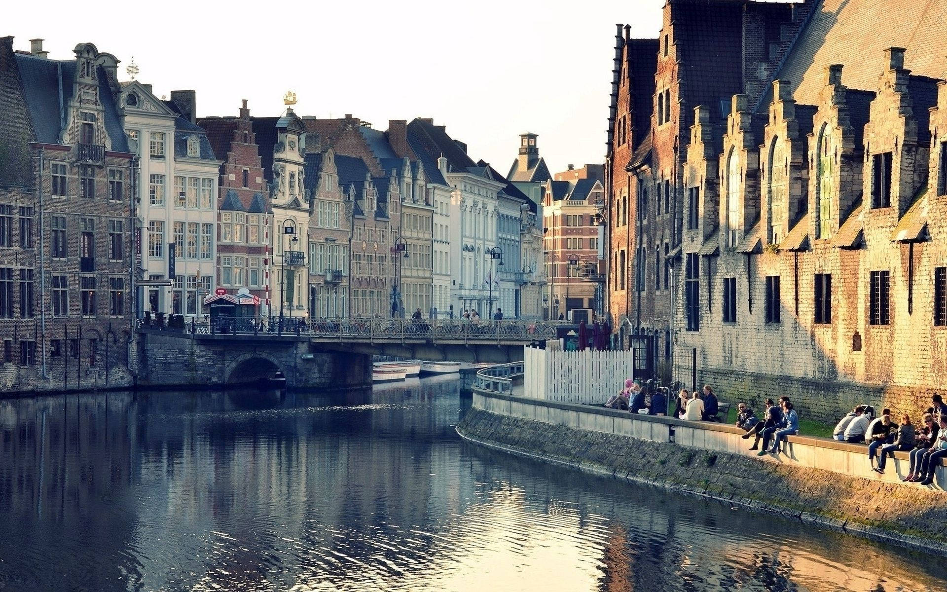 A Canal With Buildings On Either Side Background