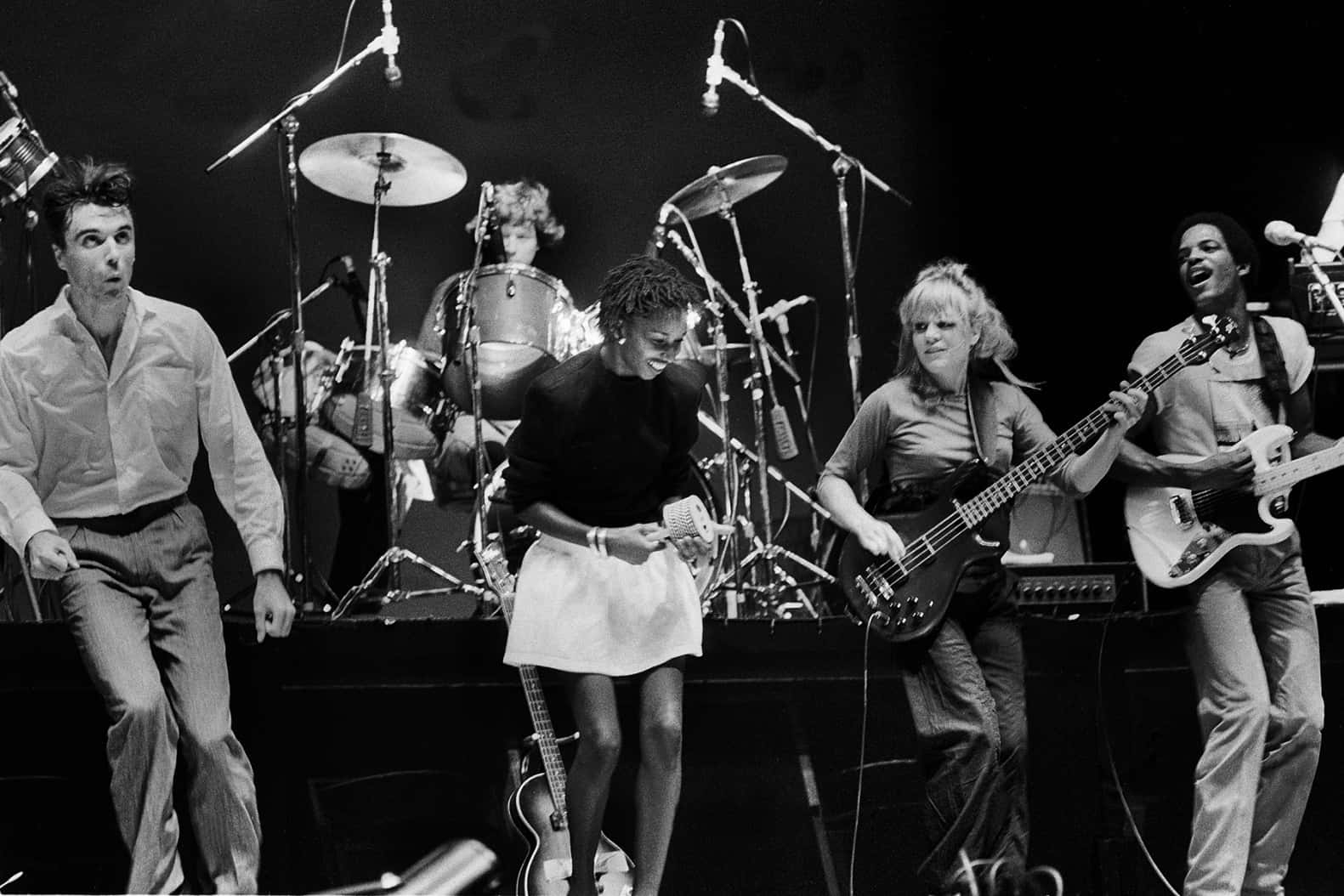 A Captivating Shot Of The Team Of Talking Heads In Their Element, On Stage. Background