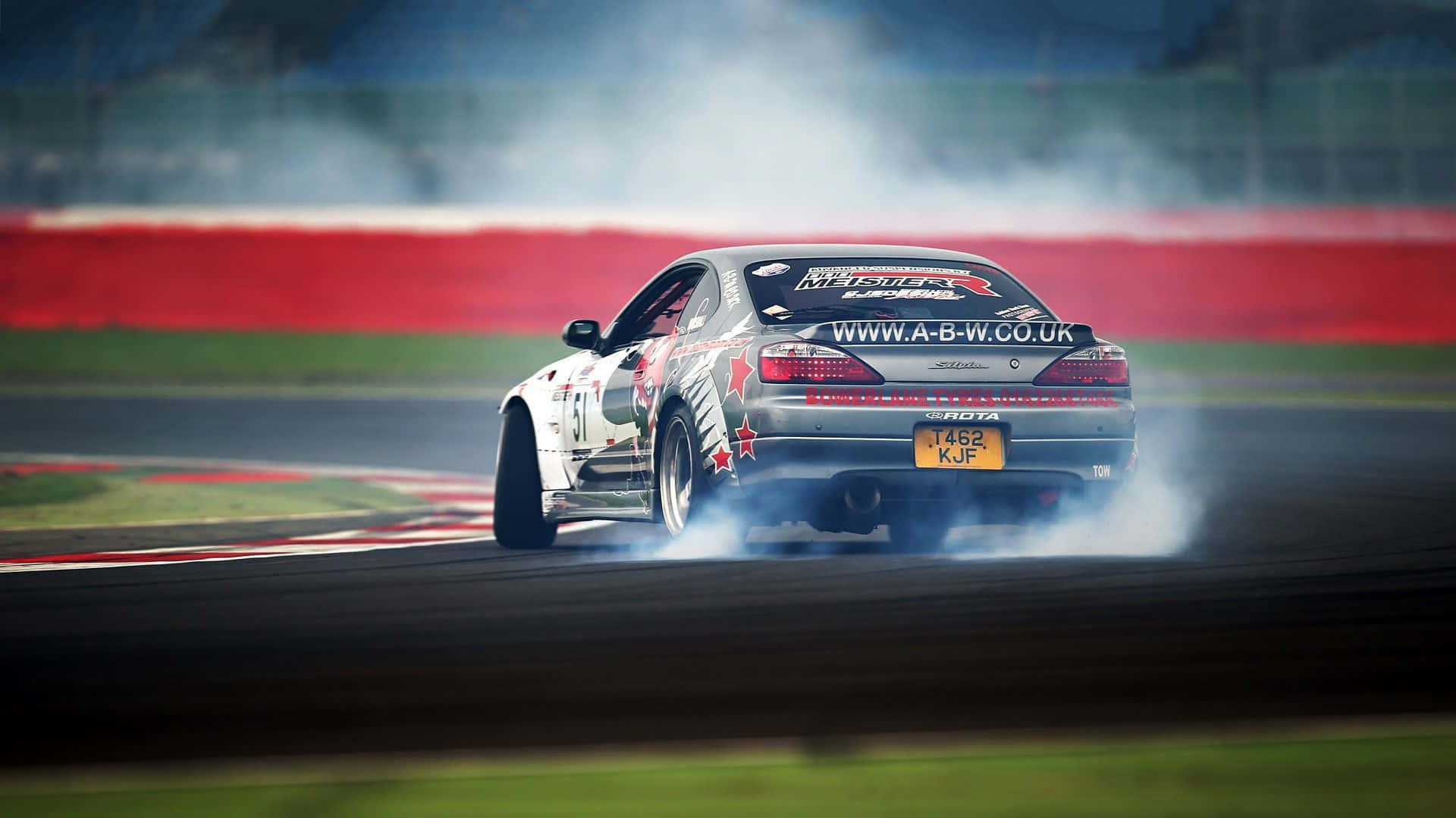 A Car Is Drifting On A Track With Smoke Coming Out Of It