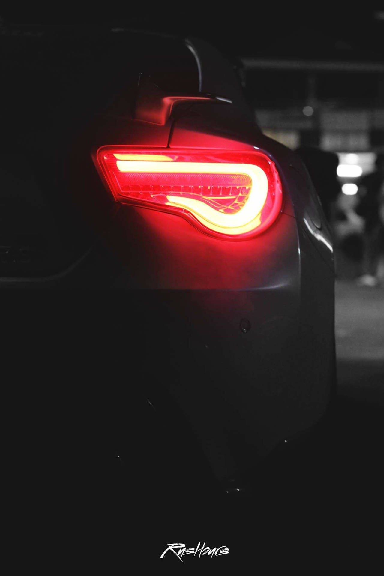 A Car With A Red Tail Light In The Dark Background