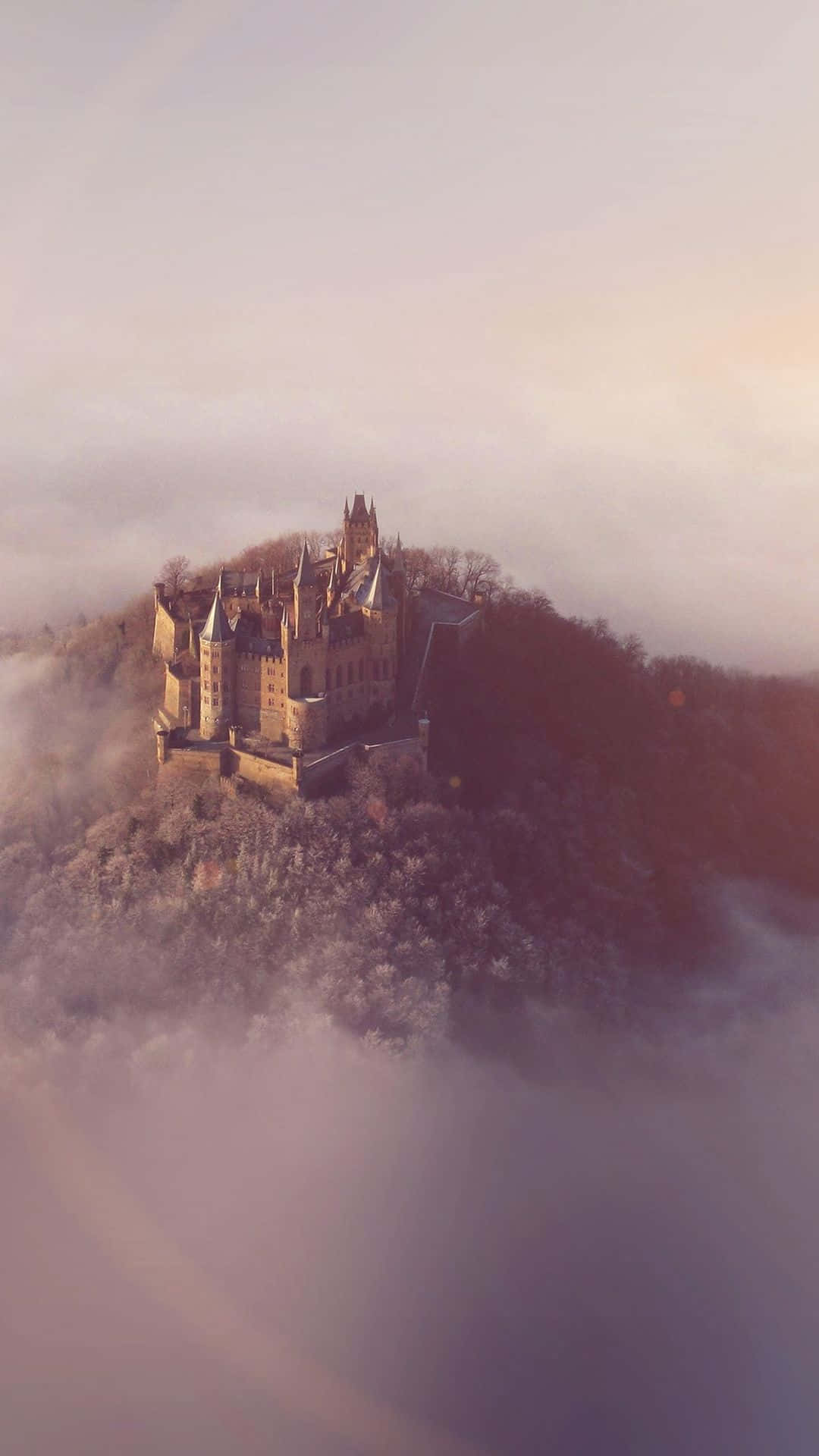 A Castle Is Sitting On Top Of A Hill In The Fog