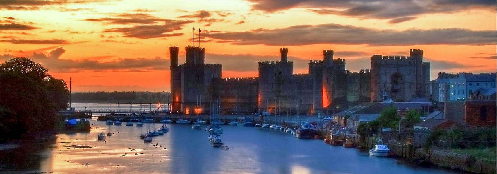 A Castle With Boats On The Water At Sunset