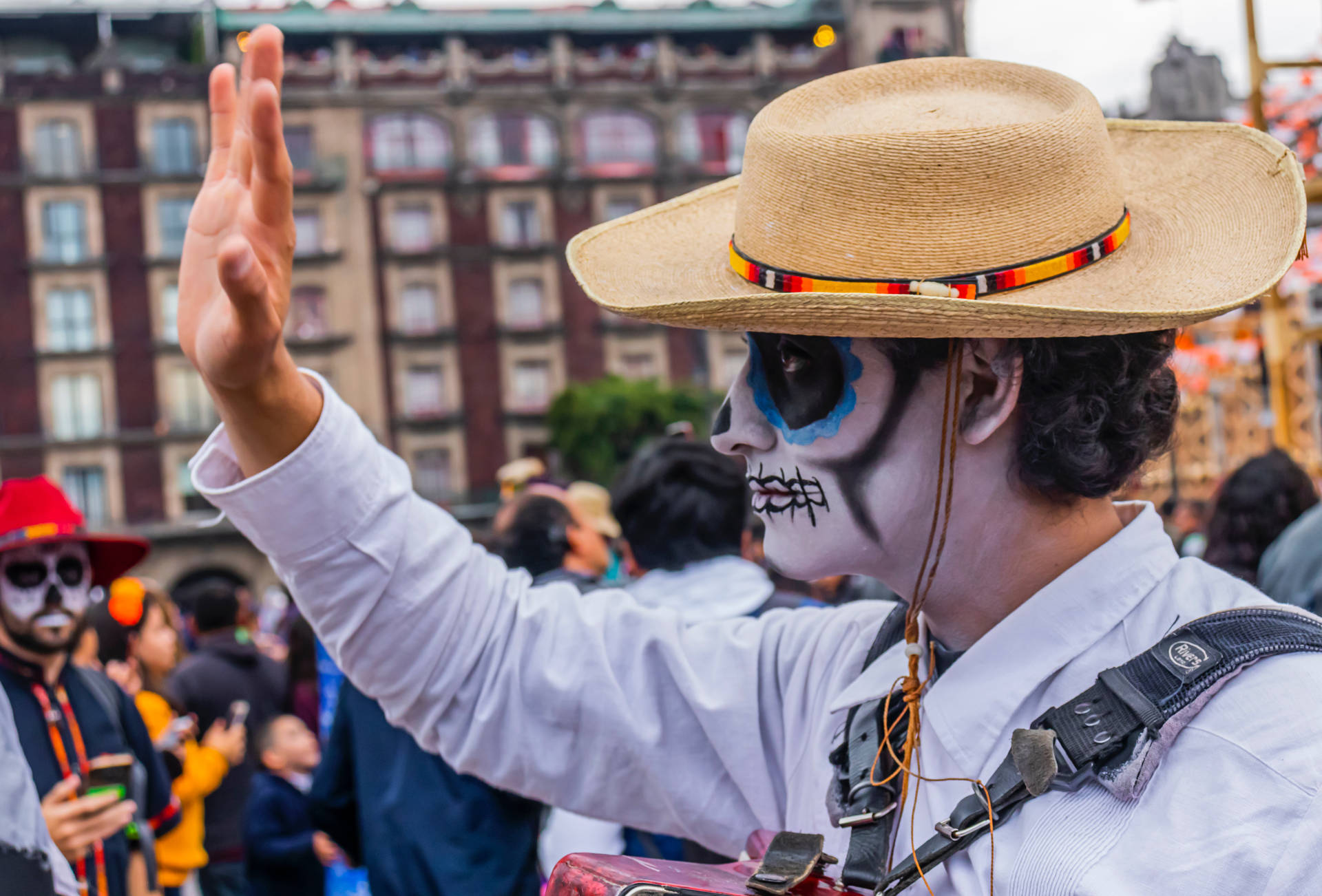 A Cheerful Mexican Man Waving To A Crowd Background