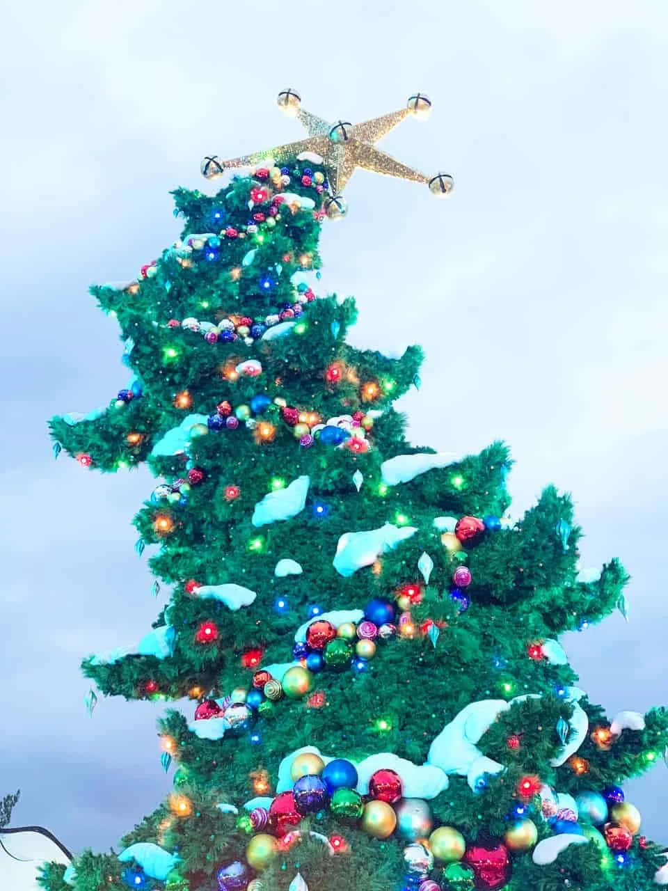 A Christmas Tree With A Lighted Ornament On Top Background