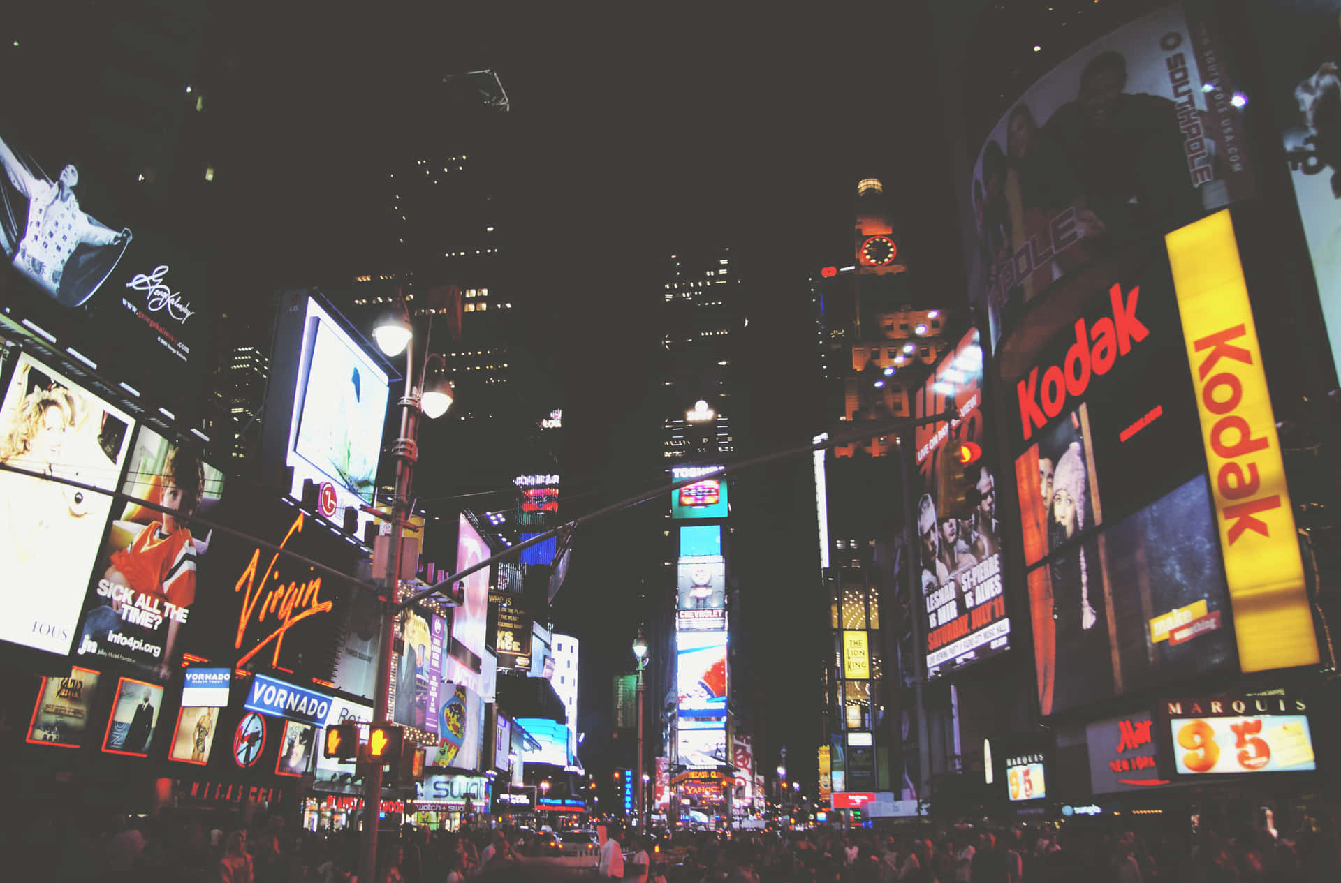 A City At Night With Many People Walking Around Background