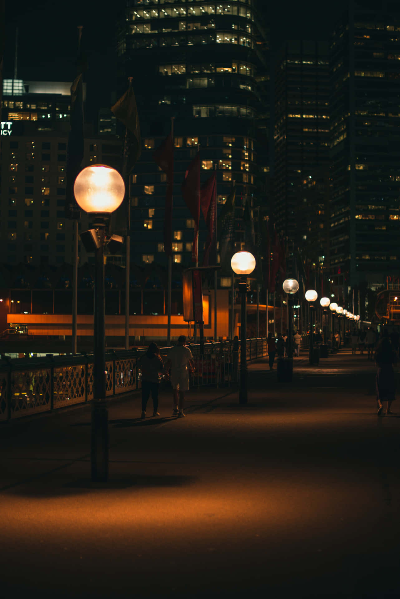 A City At Night With People Walking Along The Sidewalk