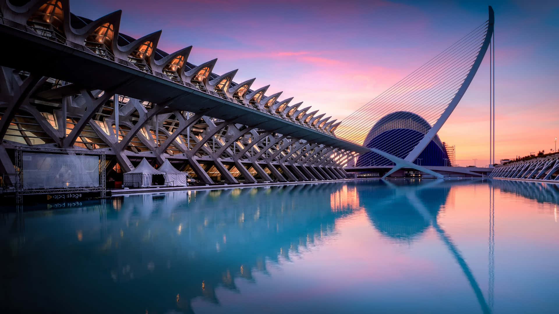A City At Sunset With A Large Building And A Pool Background