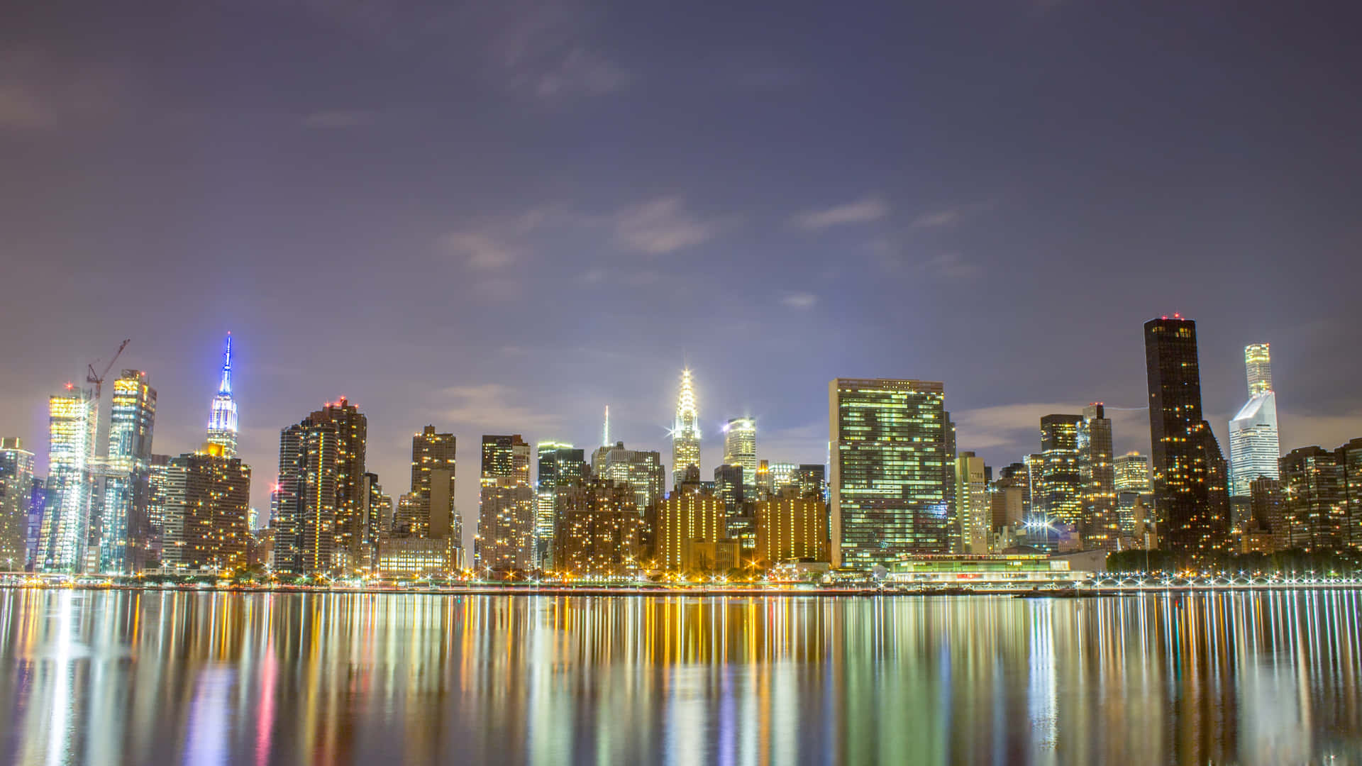 A City Skyline Is Reflected In A Body Of Water Background