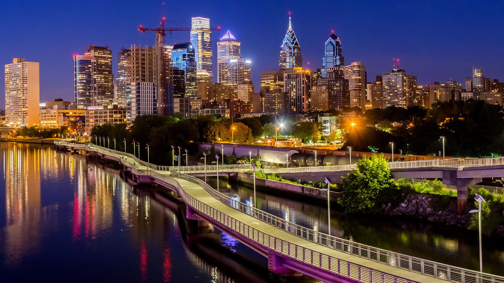 A City Skyline With A Bridge And River At Night Background