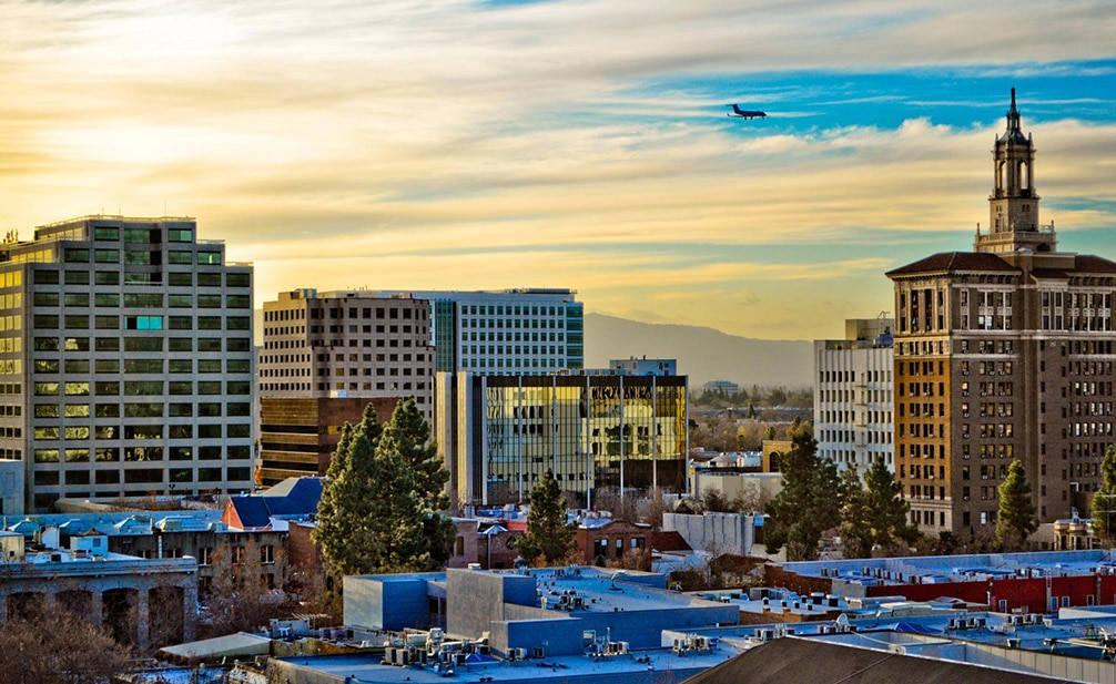 A City Skyline With A Plane Flying Over It Background