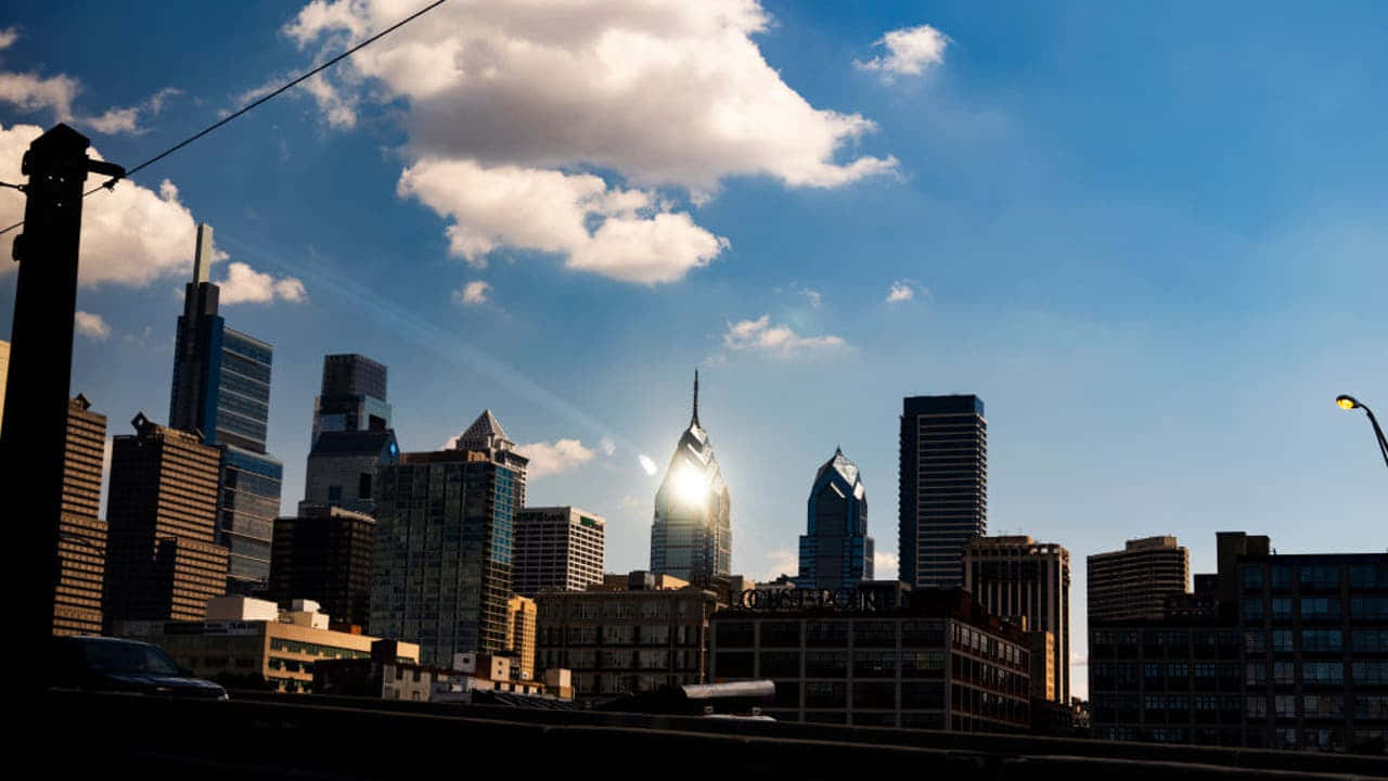 A City Skyline With Clouds And A Bridge Background