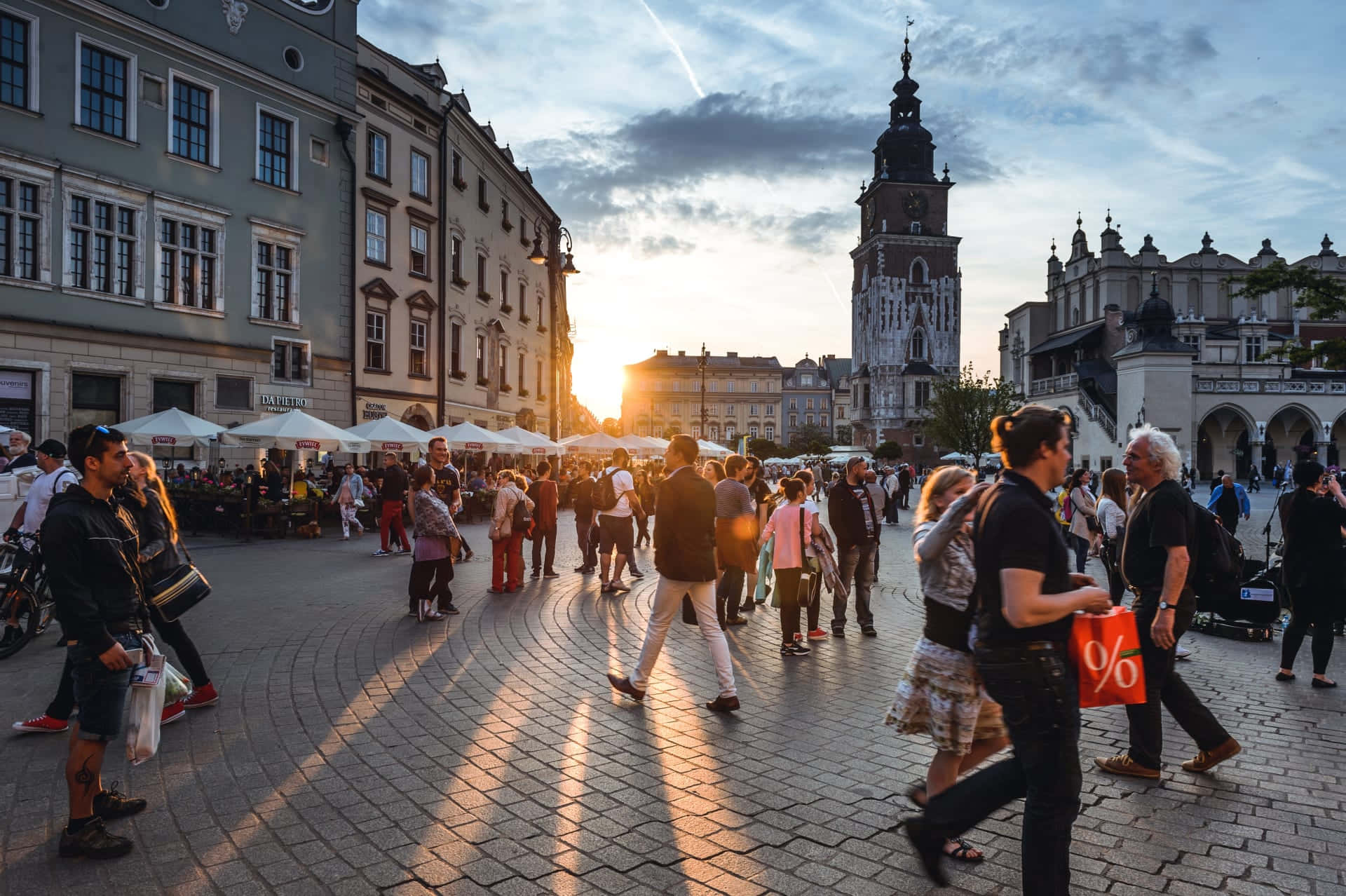 A City Square With People Walking Around At Sunset Background