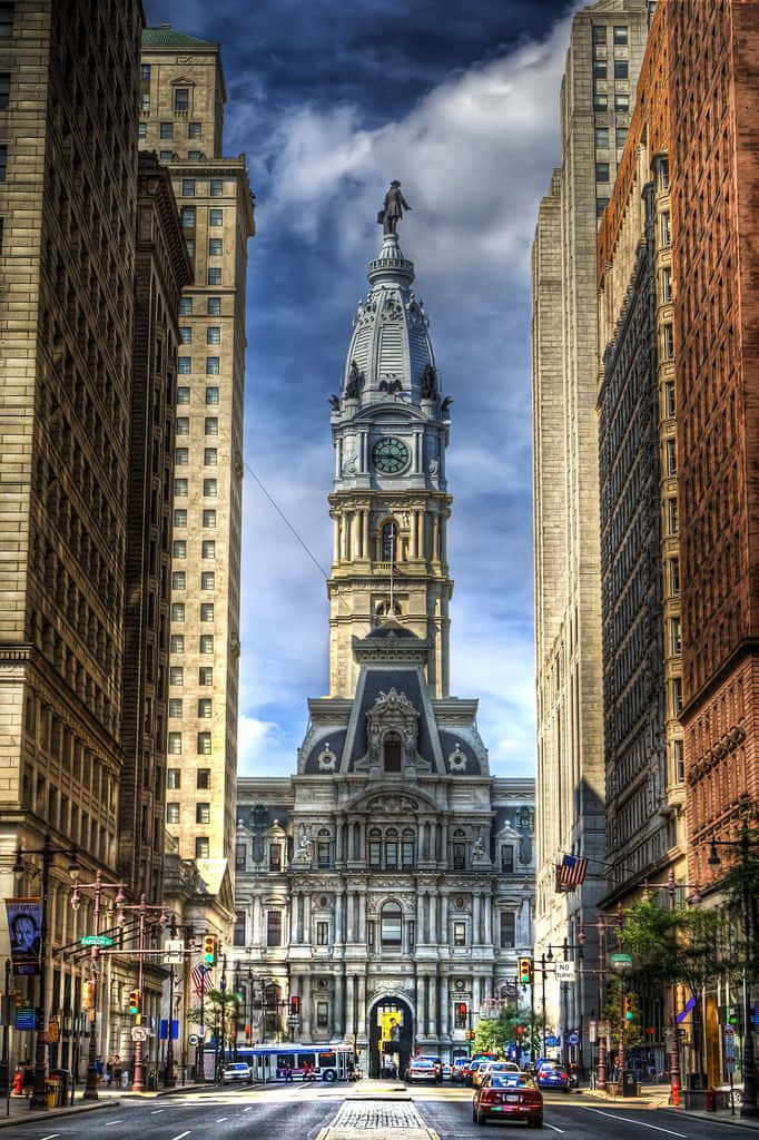 A City Street With Tall Buildings And A Clock Tower Background