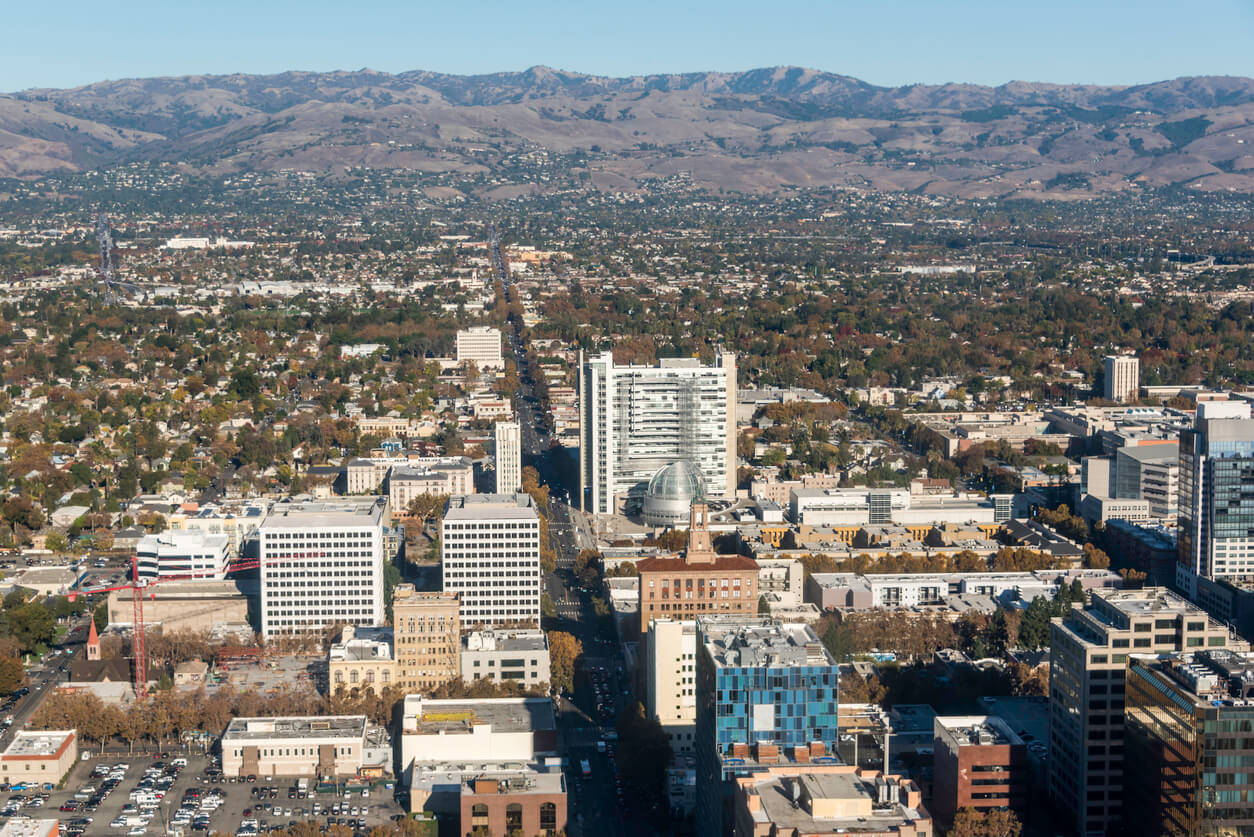 A City With Tall Buildings And Mountains In The Background Background