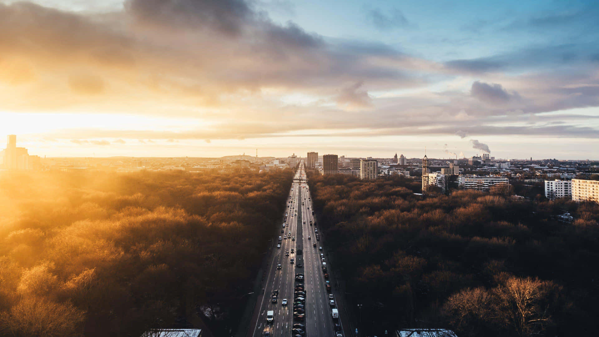A City With Trees And A Highway At Sunset Background