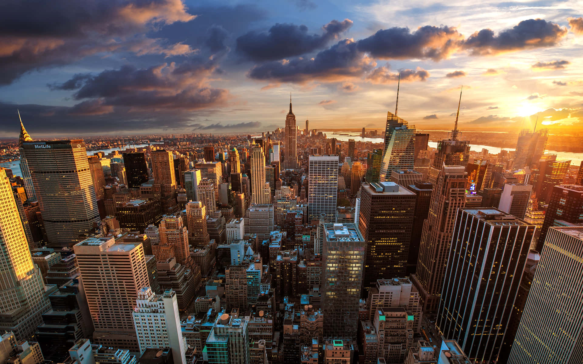 A Cityscape With Buildings And Clouds At Sunset Background