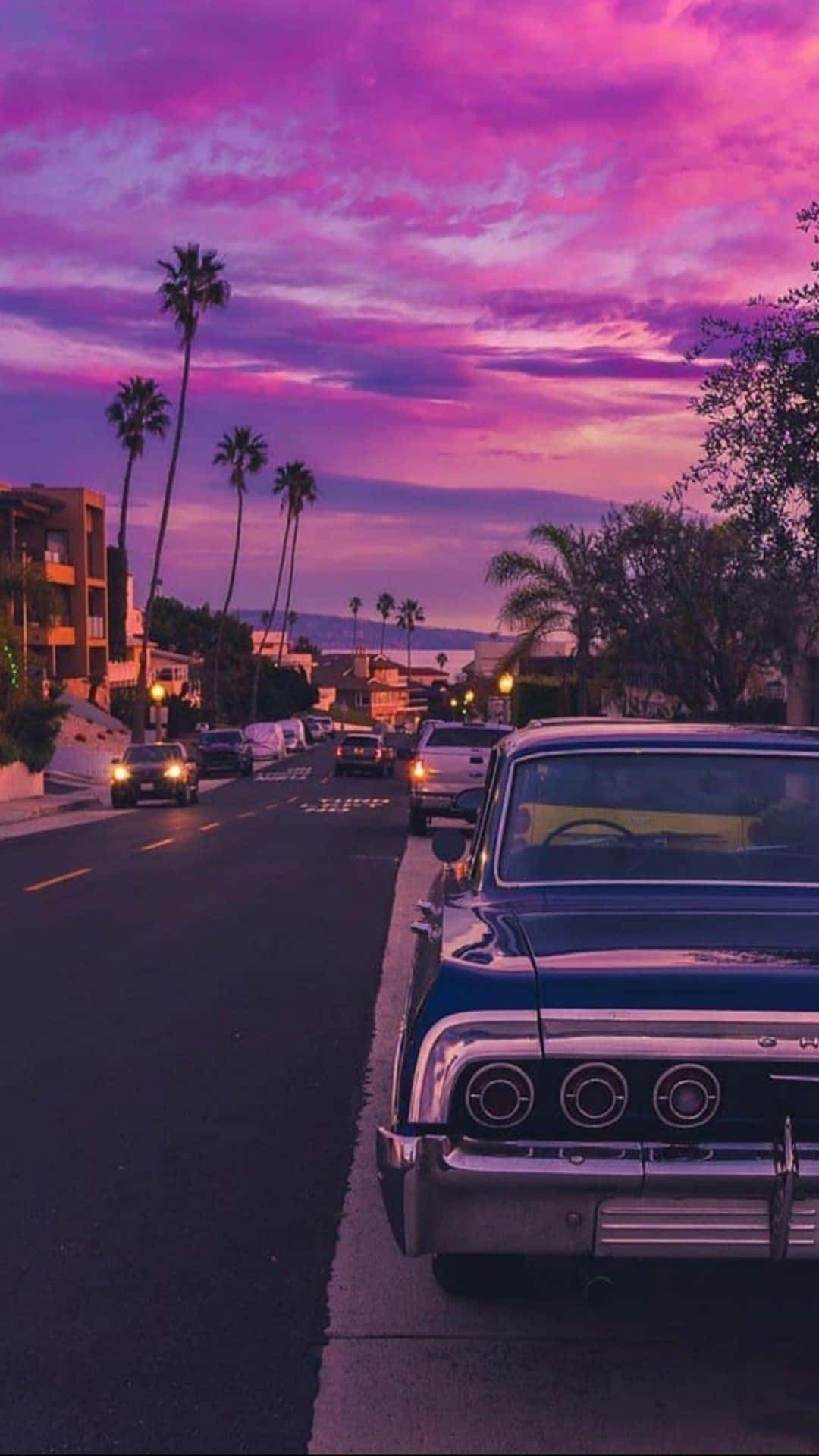 A Classic Car Parked On The Street At Sunset Background
