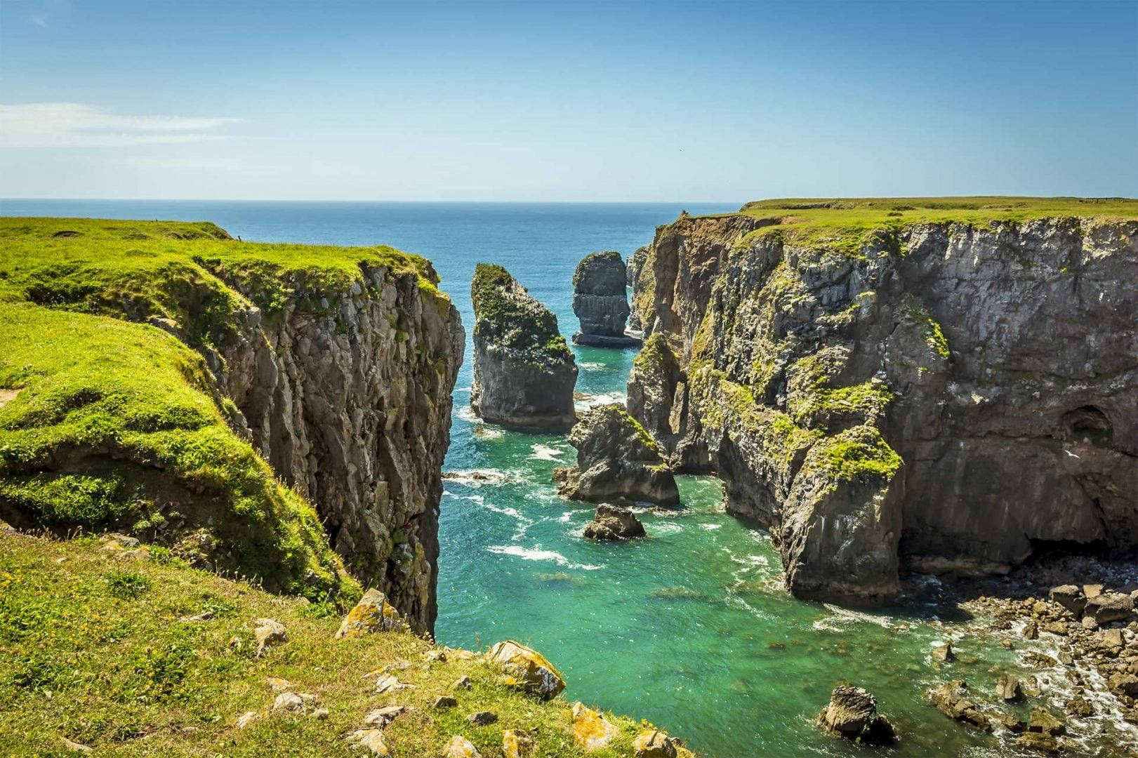 A Cliff With Green Grass And Ocean