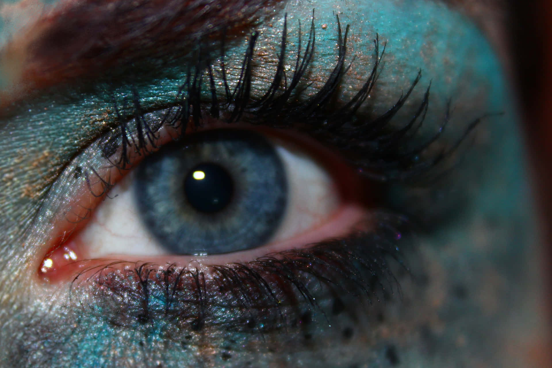 A Close Up Of A Woman's Eye With Blue Makeup Background