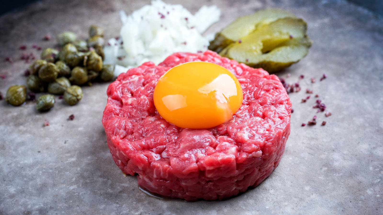 A Close-up View Of Gourmet Steak Tartare Topped With Spicy Sauce And A Fresh Raw Egg Yolk Background