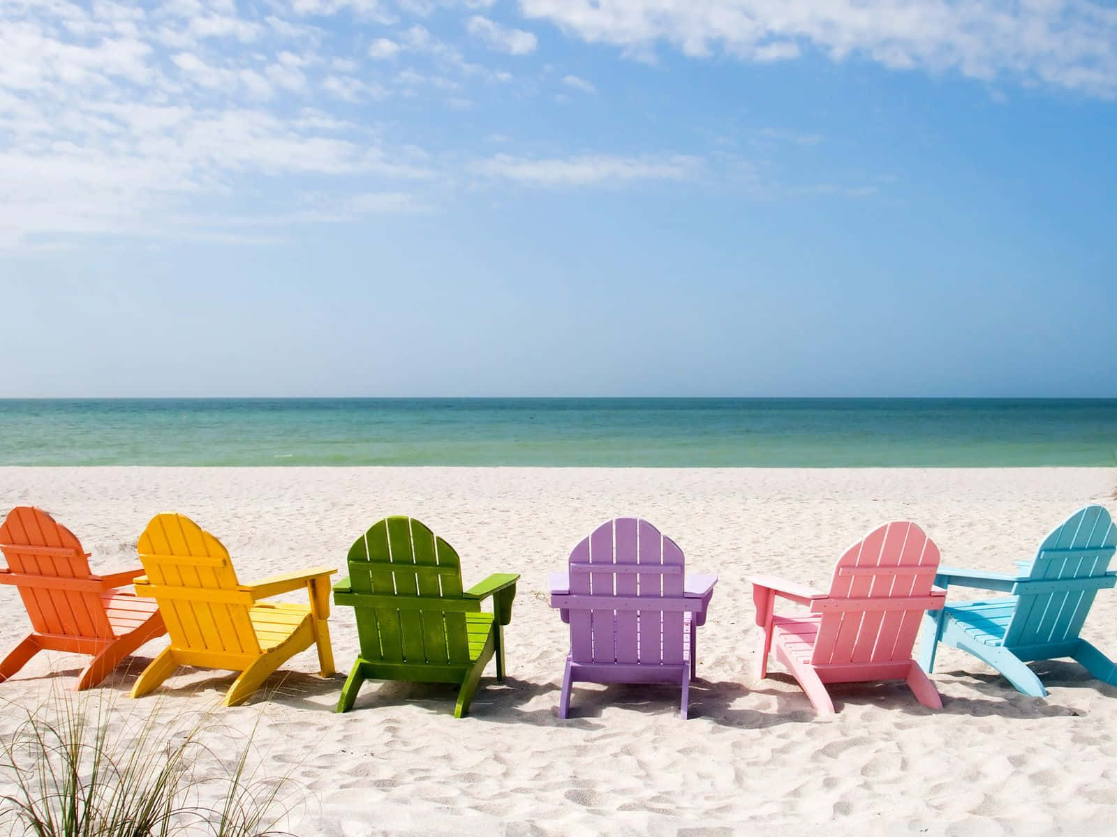 A Colorful Array Of Chairs By The Beach Background