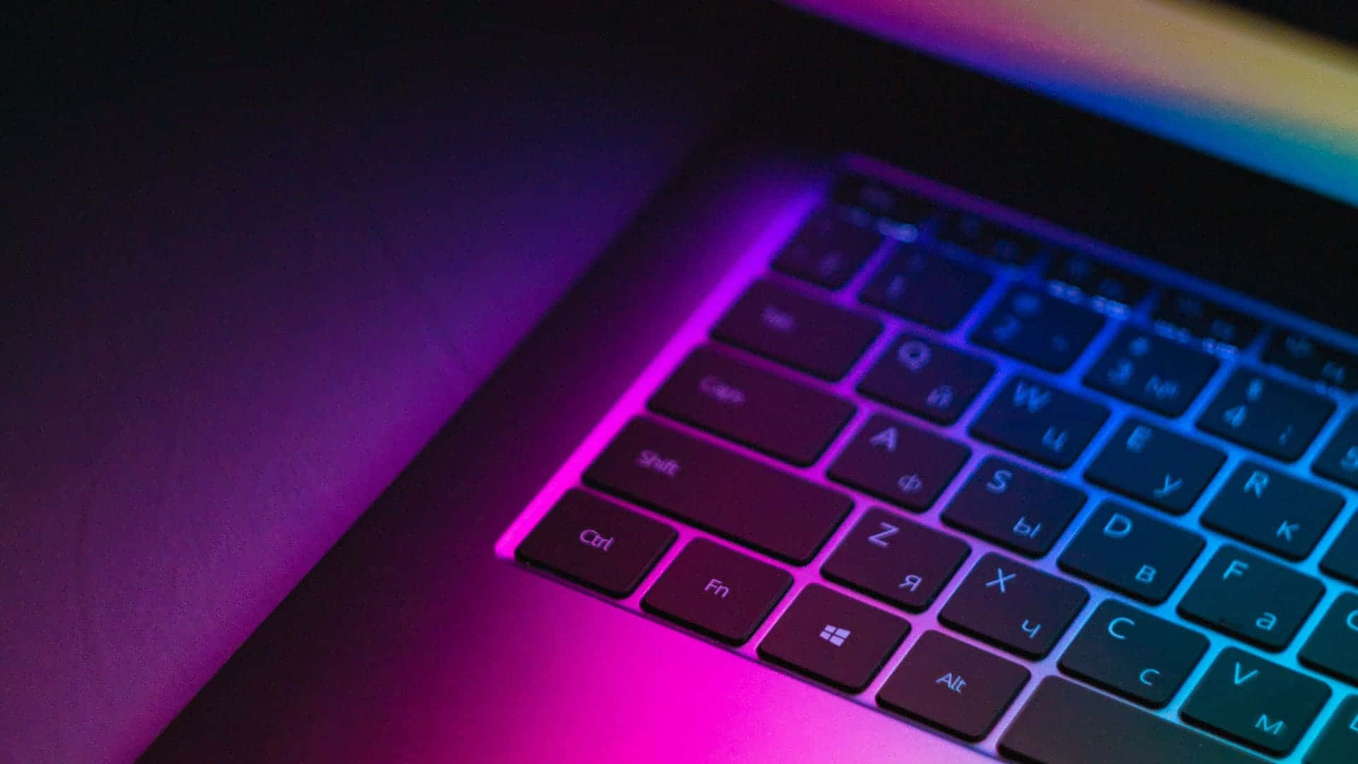 A Colorful Laptop Keyboard With A Rainbow Light Background