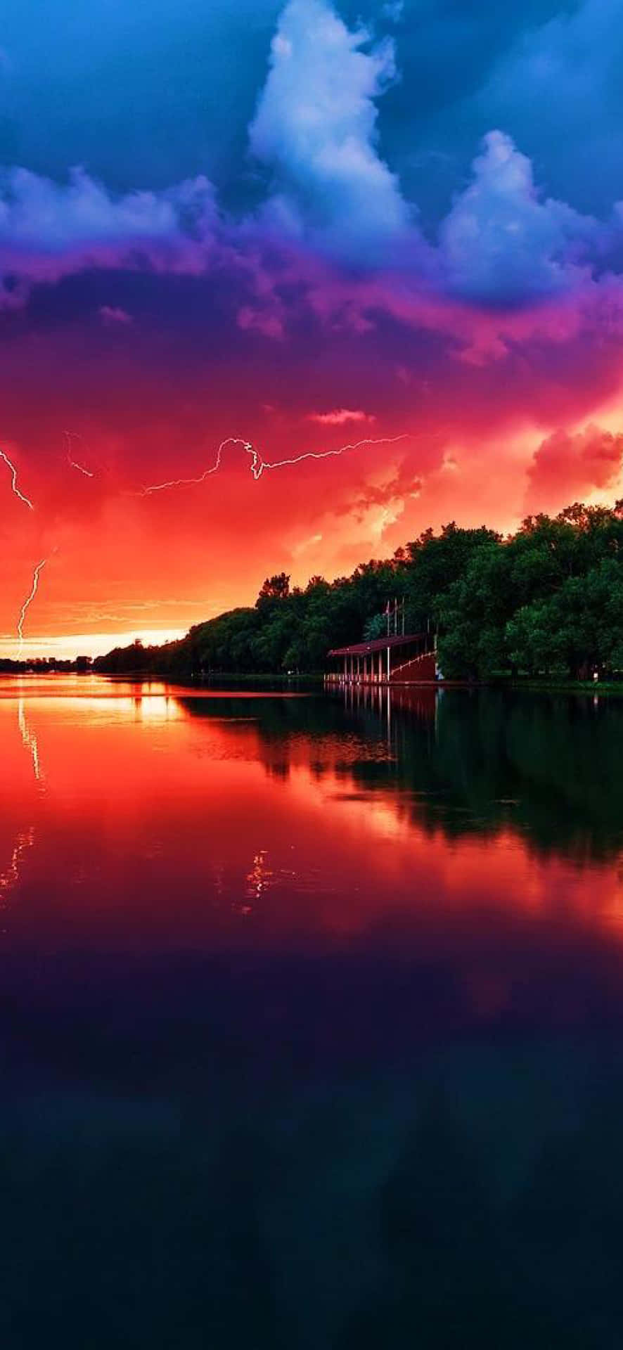 A Colorful Sunset Over A Lake With Lightning Background