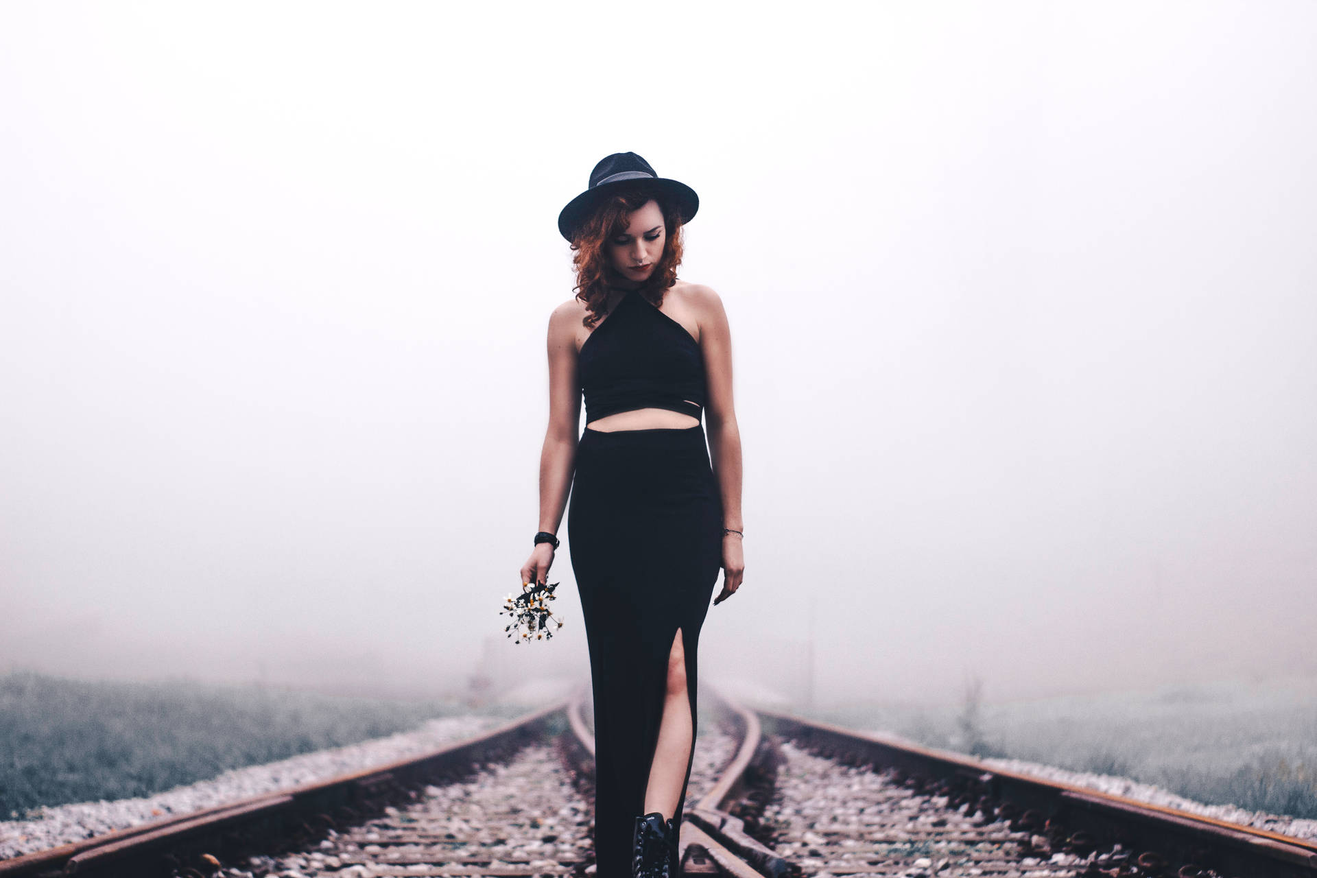 A Confident Young Woman Stands In The Middle Of A Empty Train Railway Background