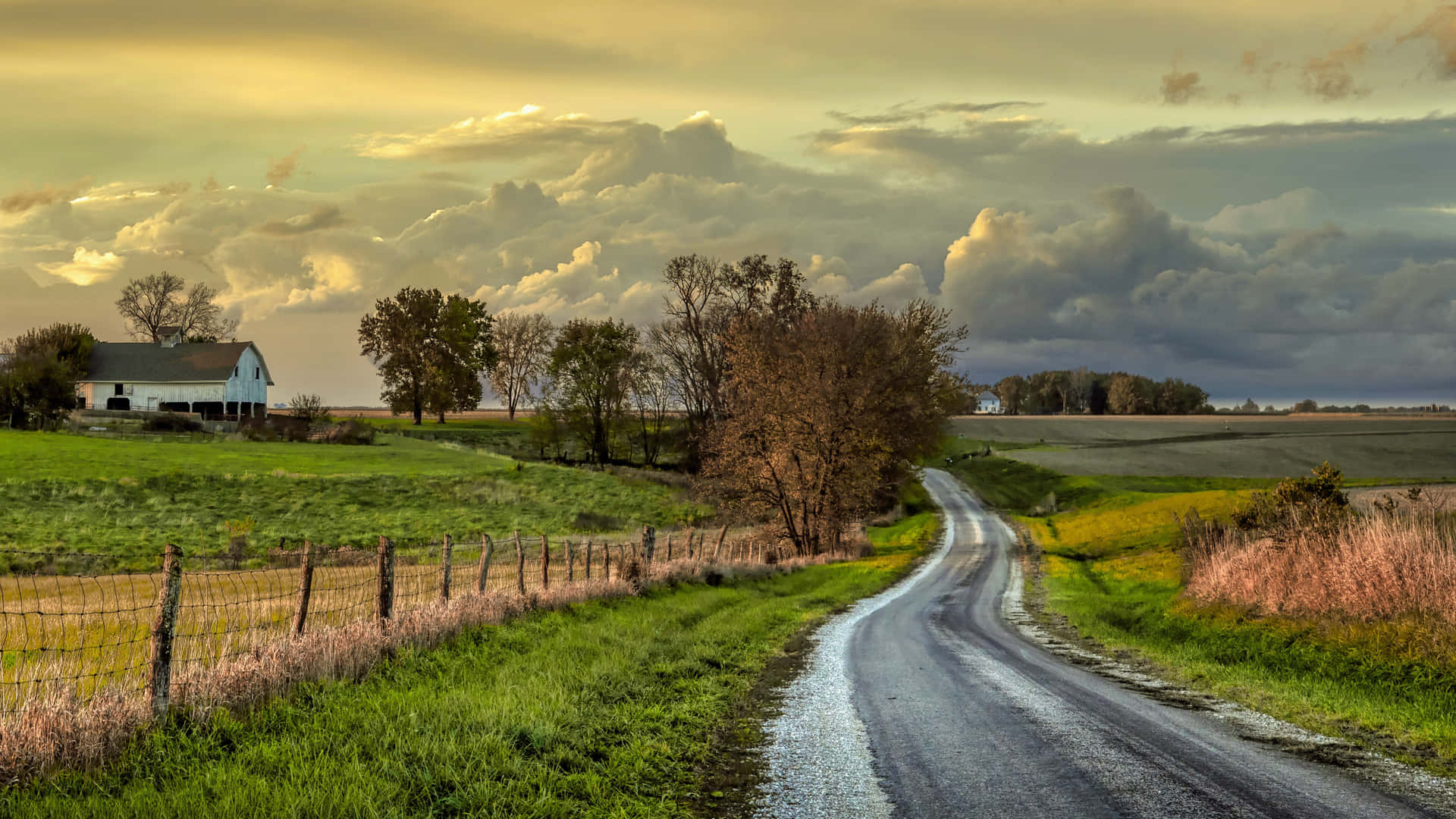 A Country Road With A Farmhouse In The Distance Background
